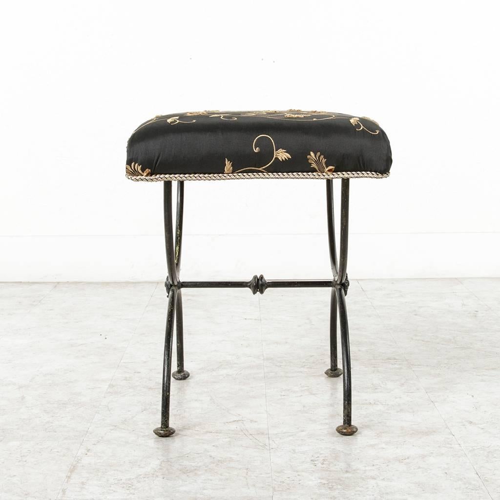 A design classic, this mid-century French bench is beautifully and simply designed with two semi circles meeting with one central crossbar. Newly upholstered in a black taffeta with stitched raised gold floral chinoiserie, this elegant piece can