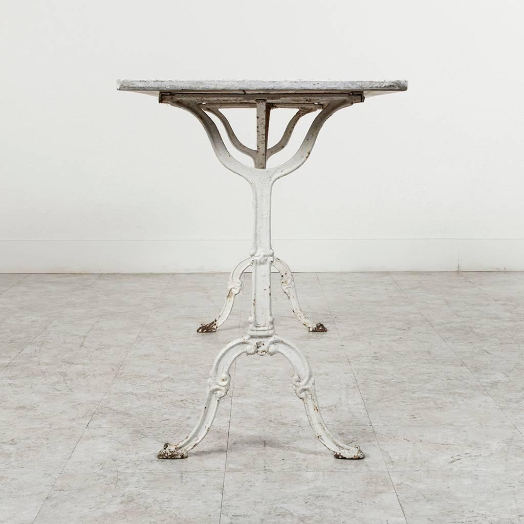 A rare find at a length of over 5 feet, this cast iron bistro table has a beautifully aged patina to its white finish. A versatile piece, this table could function as a desk, console, sofa table or small dining piece for a breakfast nook or outdoor