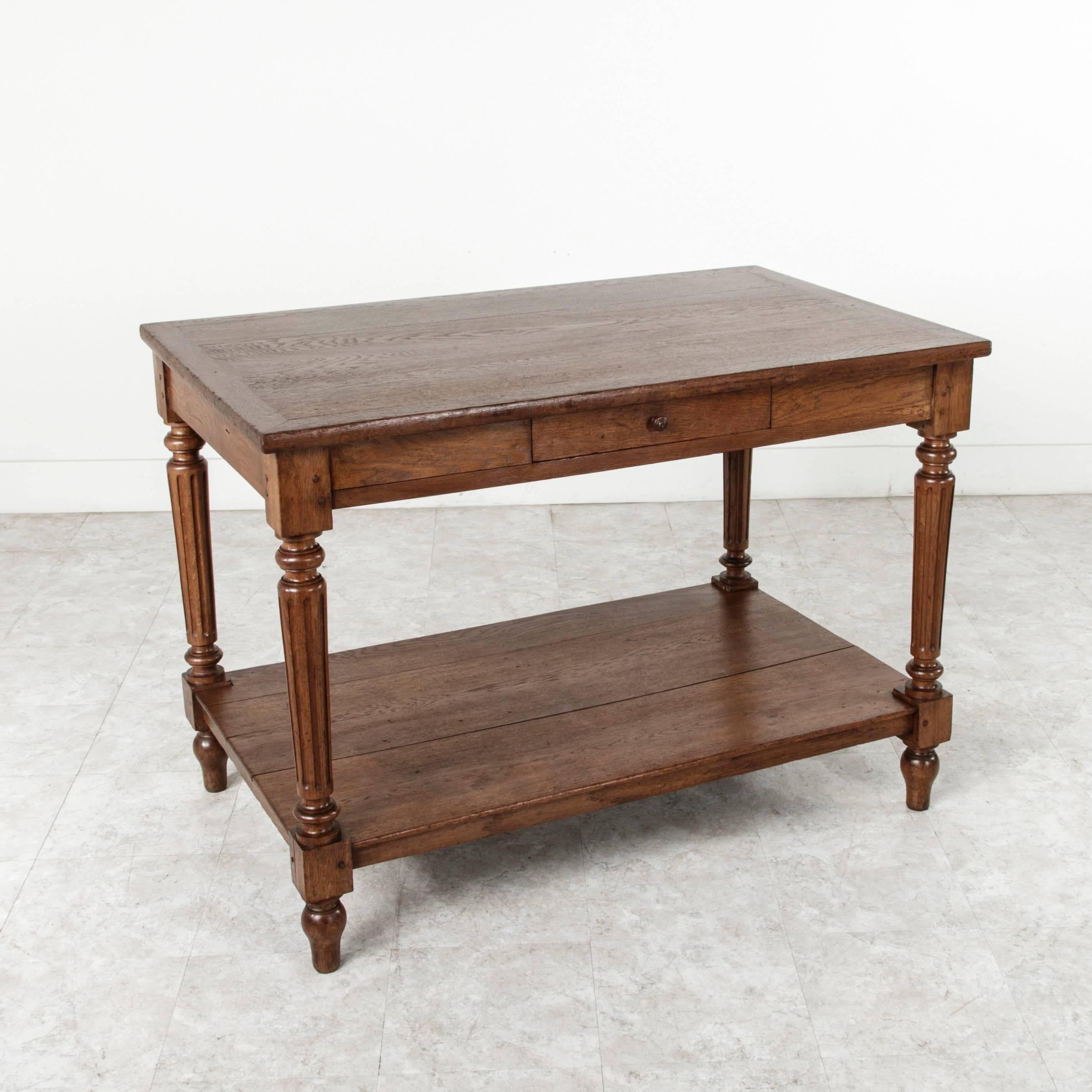 Constructed of hand pegged solid oak, this fabric presentation table was used in a fabric shop to present large swaths of fabric to customers. Its two tiers, drawer, and height make this piece ideal for use as a kitchen island. Additionally, its