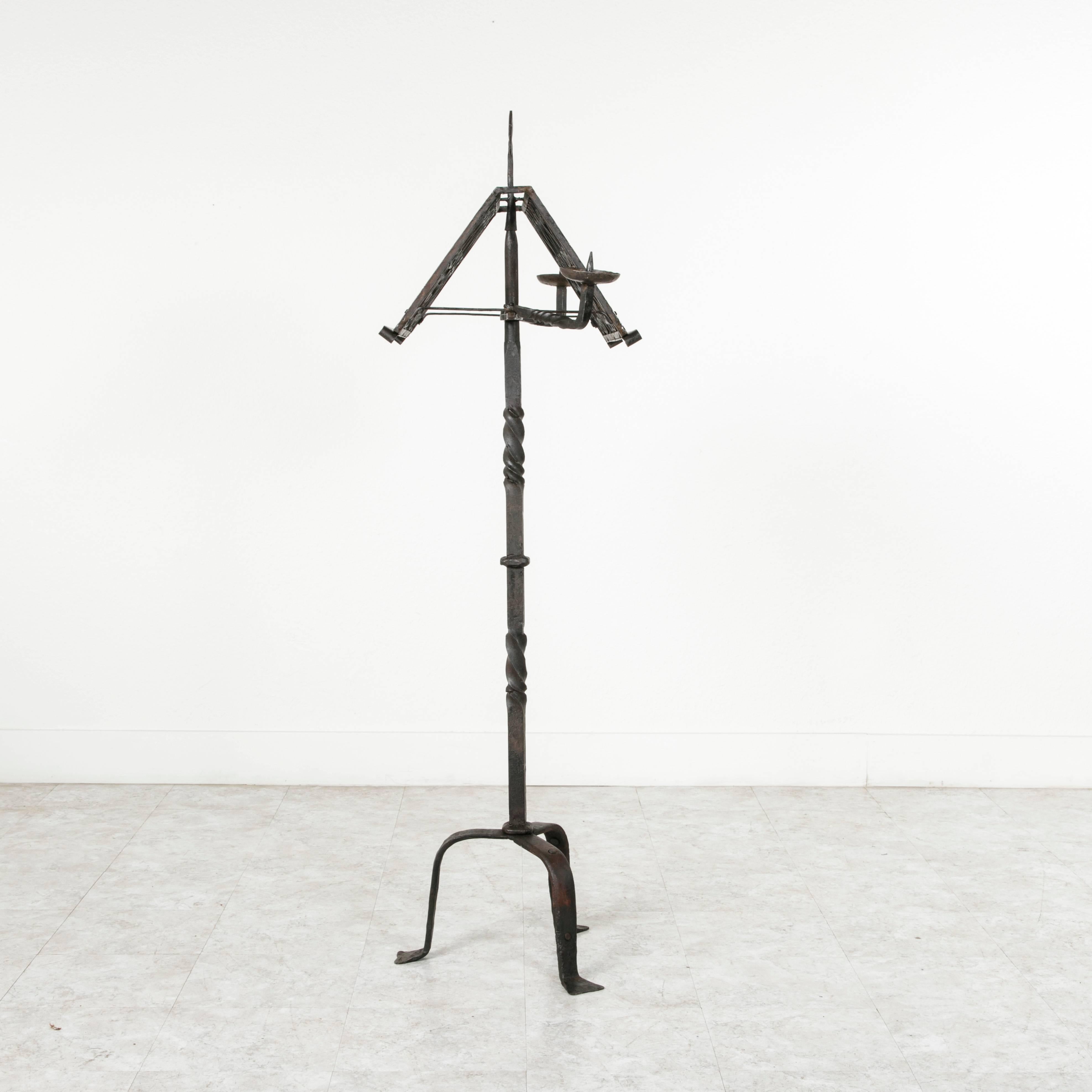 This impressive hand-forged iron music stand is designed so that a musician can stand on each side. Candleholders extend on the left and right to light sheet music and a central fleur-de-lys rises from the top. The age and heavy hand-forged iron of