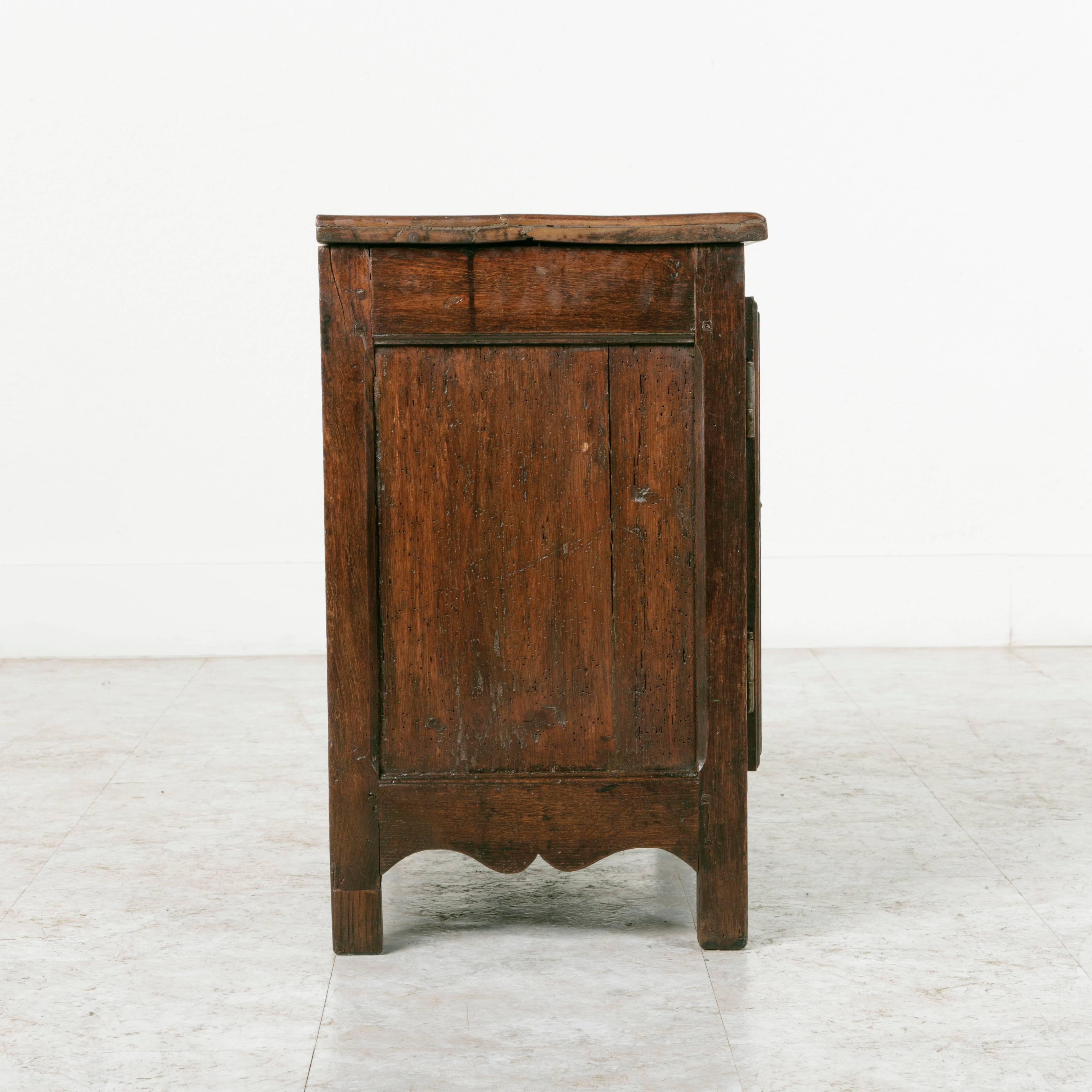 This beautifully aged small side cabinet was created in the late 1700's in Normandy. A simple and well constructed piece of solid hand pegged oak, this cabinet still has its original iron latch. This piece is an excellent scale for use as a