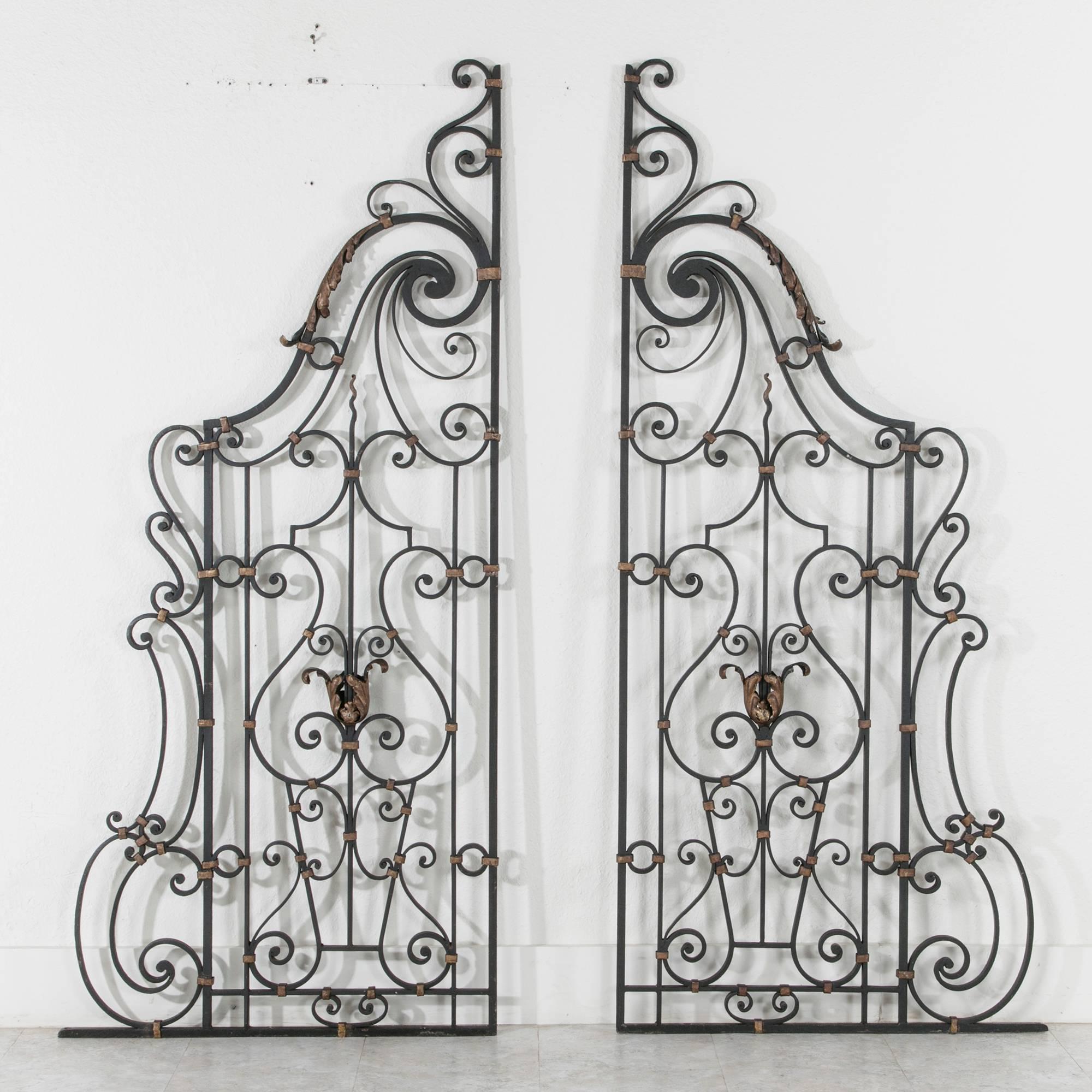 This stunning pair of hand-forged iron partitions was created in Deauville, France in the Art Deco era. A rare find, they are double sided with gold painted metal detailing. This set is made with mounting holes along the lower iron bar and along the