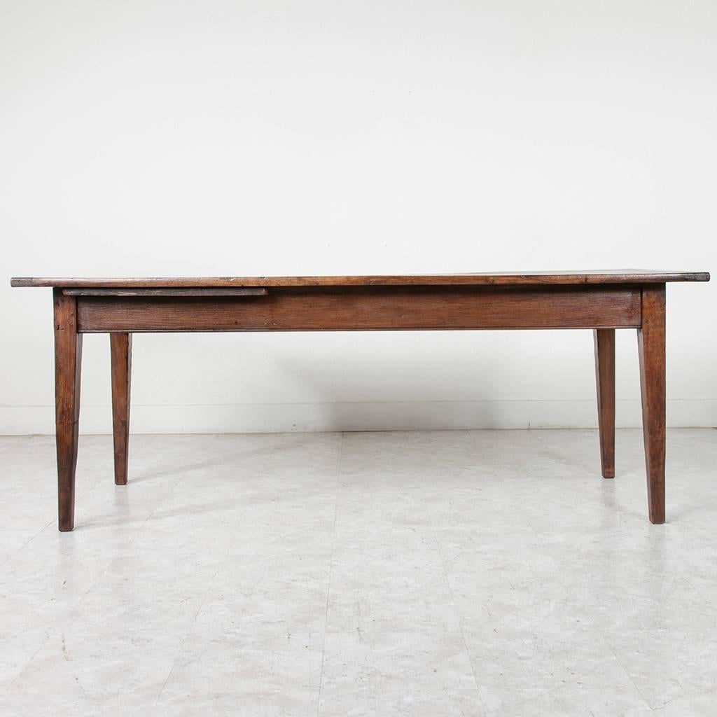 This artisan made farm table is made of dark solid hand pegged French oak. A simple drawer on one side was designed to hold bread knives at the table, while the other side holds a pull-out cutting board. This piece's clean elegant lines will blend