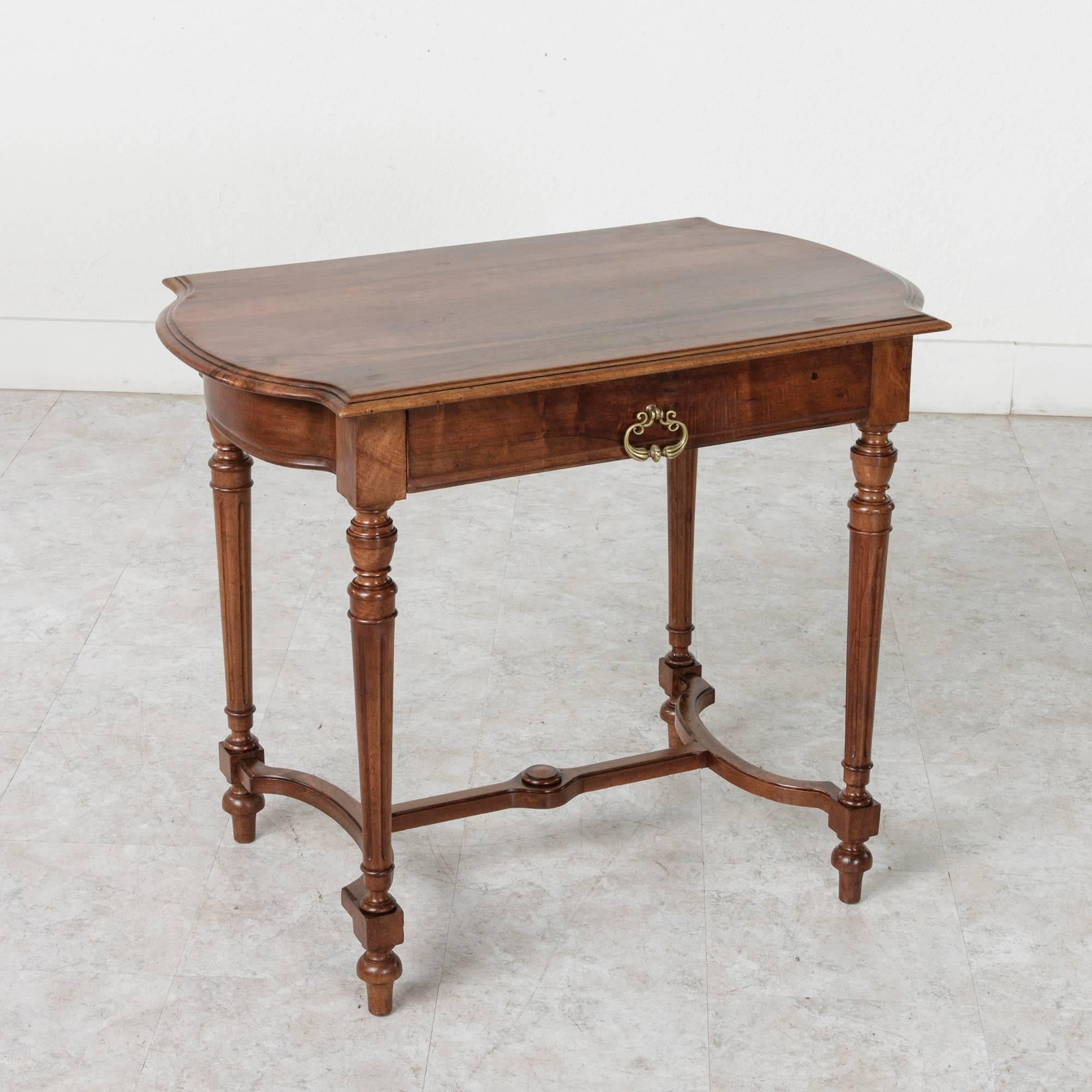 This late 19th century Louis XVI style writing table is constructed of solid walnut. The simple, clean lines of this piece allow the deeply contrasting heart grain of its walnut to shine. Finished on all sides, this piece would make an excellent