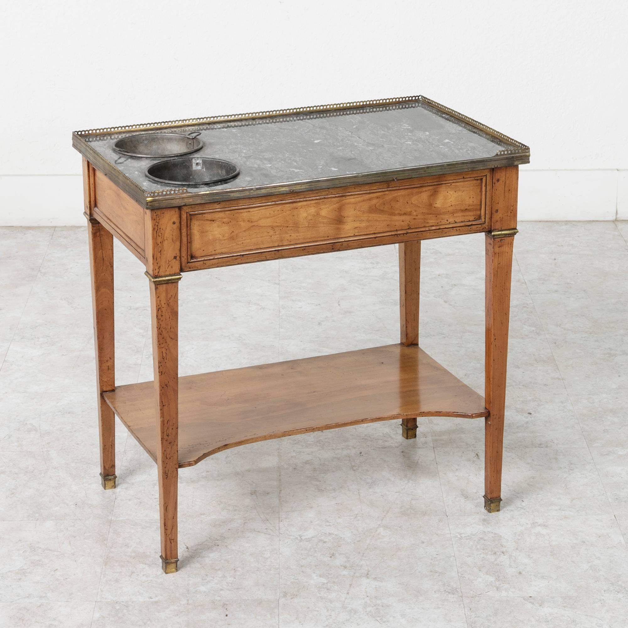 This rare 19th century Louis XVI style walnut side table features a Saint Anne marble top surrounded by a bronze gallery and bronze sabots on its feet. Two removable bronze buckets that rest in the marble top serve to chill wine or champagne. A