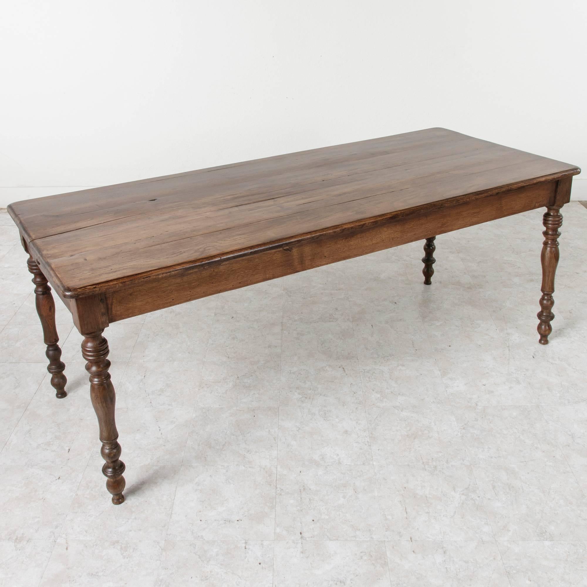 The warm, naturally aged wood of this antique French farm table will bring a sense of history to a dining or kitchen space. Created of hand pegged oak by artisans in Normandy at the beginning of the 20th century, this table features a drawer on each