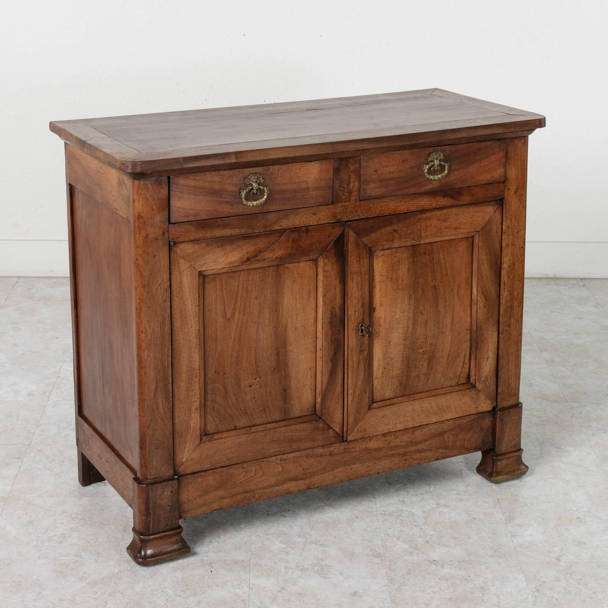 The Classic, simple lines of this 19th century Louis Philippe period buffet are at home in both contemporary and traditional interiors. Of solid walnut and hand pegged construction, this piece features two upper drawers adorned with bronze drop