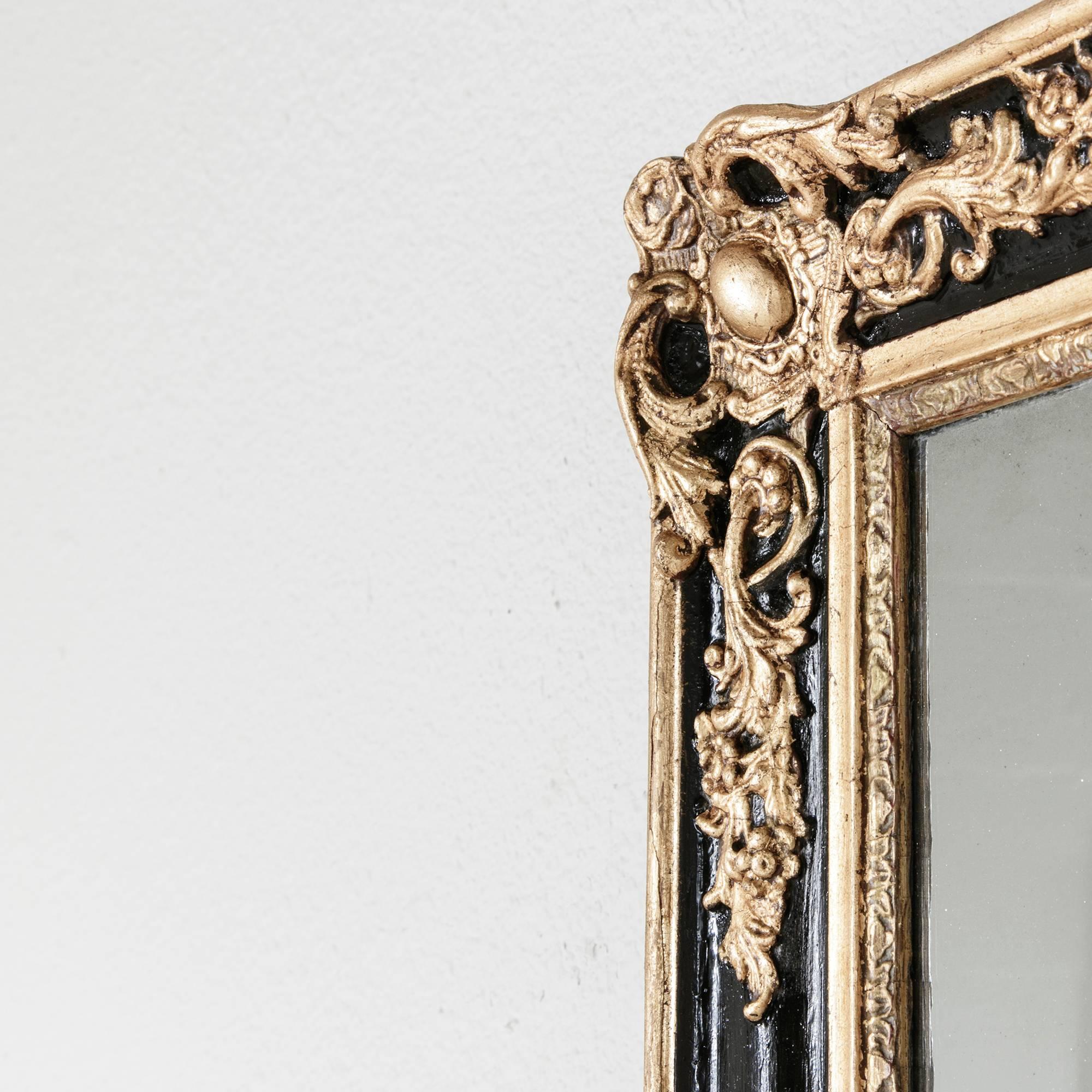 This late nineteenth century Regency style mirror features its original mercury glass. Recently refinished in black and gold leaf while still retaining its character, its hand carvings include ornate scrolls of acanthus leaves and corner medallions