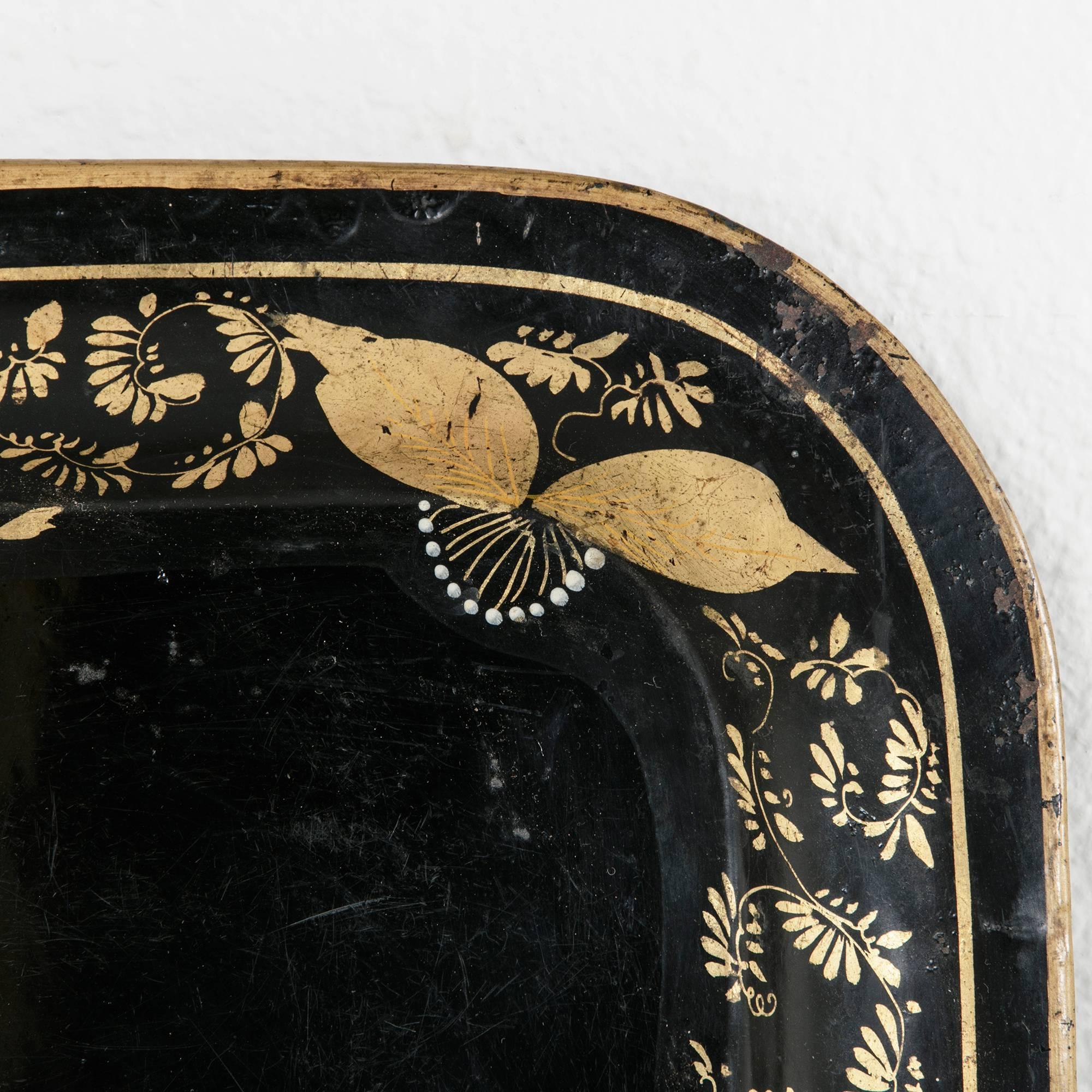 This hand-painted 19th century tray features groupings of large leaves painted in gold interspersed with delicate, curling branches around its perimeter. Its central black field would give prominence to a collection of fine objects displayed on top.