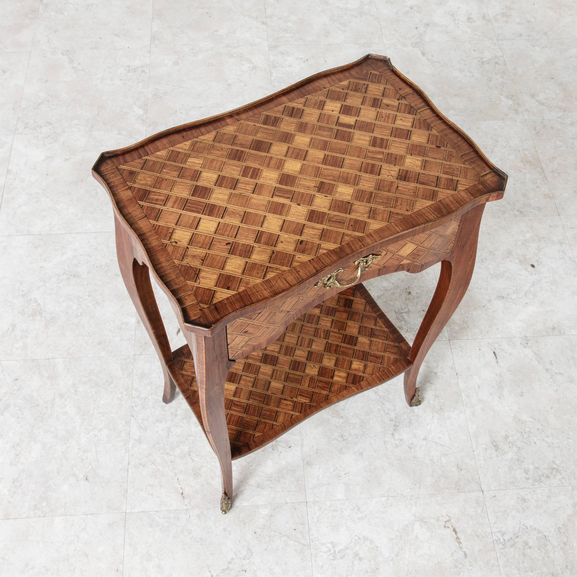 This circa 1860 Louis XV style marquetry side table or nightstand with bronze fittings features a single drawer and lower shelf. Its walnut hexagonal marquetry is featured on all sides as well as on its top and shelf. Gently curved cabriole legs