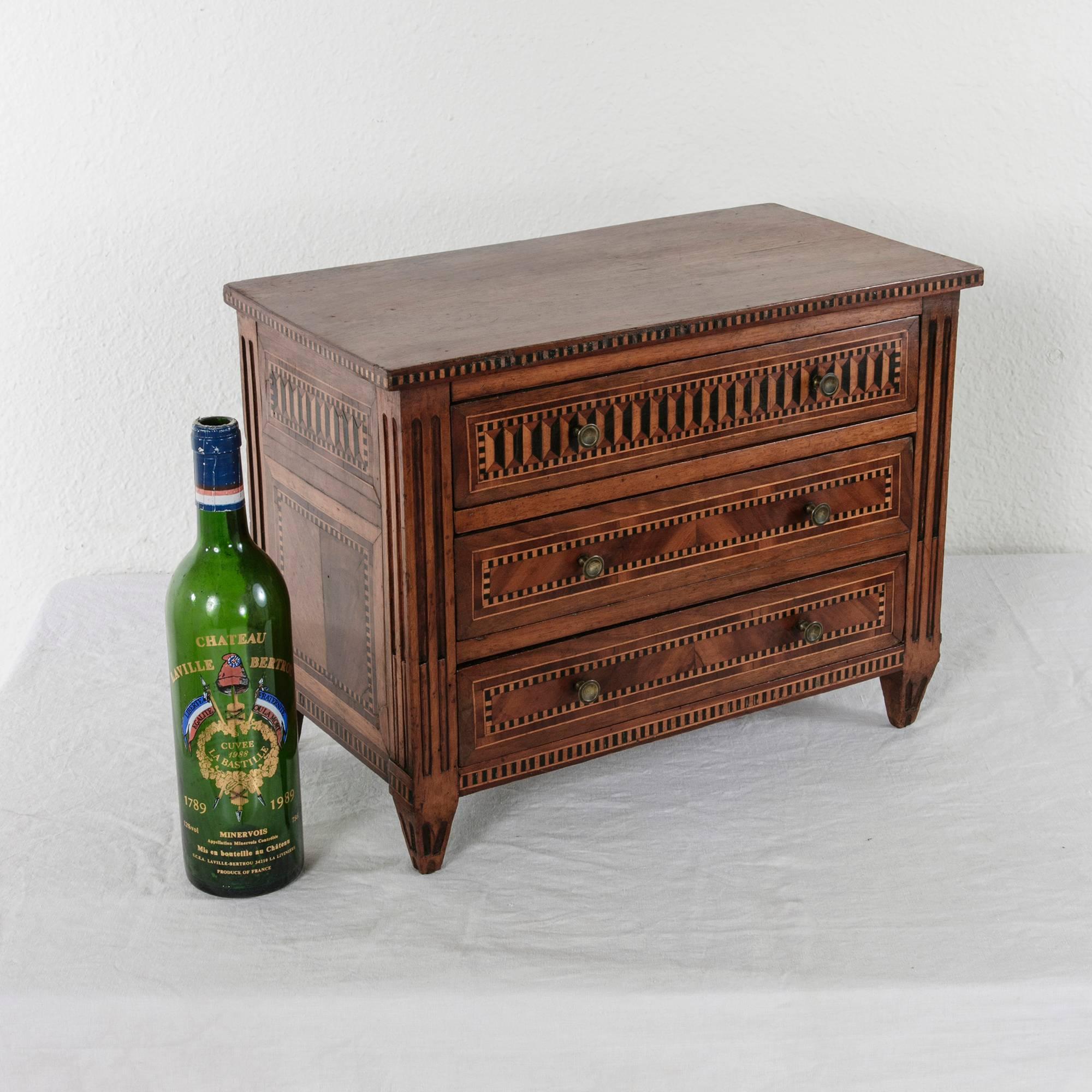 This miniature marquetry chest in the Louis XVI style is a "meuble de maitrise" or masterwork created by a cabinetmaker's apprentice to prove mastery of his craft at the end of his apprenticeship. This unusually detailed example includes