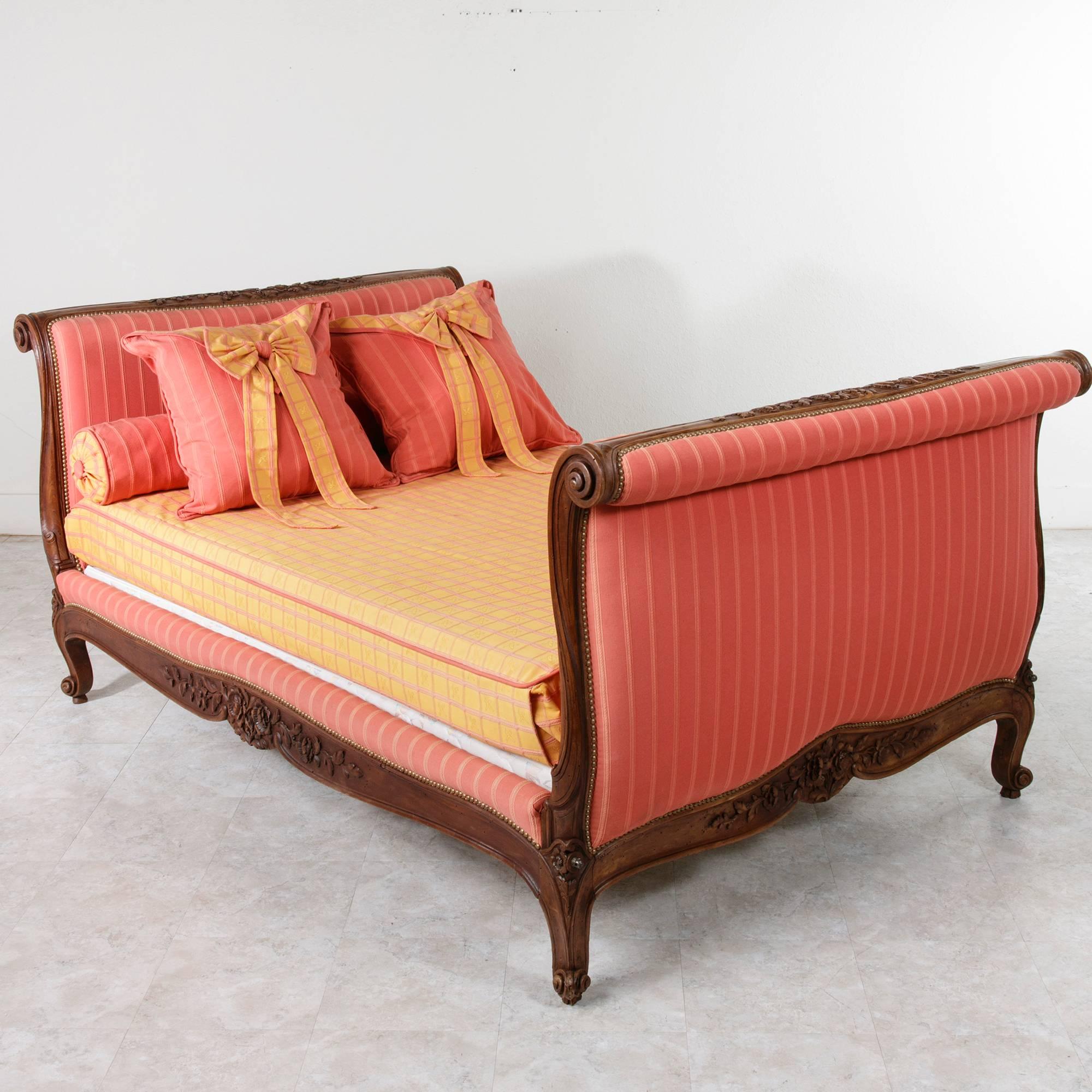 This 19th century solid walnut Louis XV style bed hails from the Provence region in Southern France. The headboard, footboard and both side rails are all lavishly hand-carved with scrolling leaves and flowers. Both head and foot boards are of the