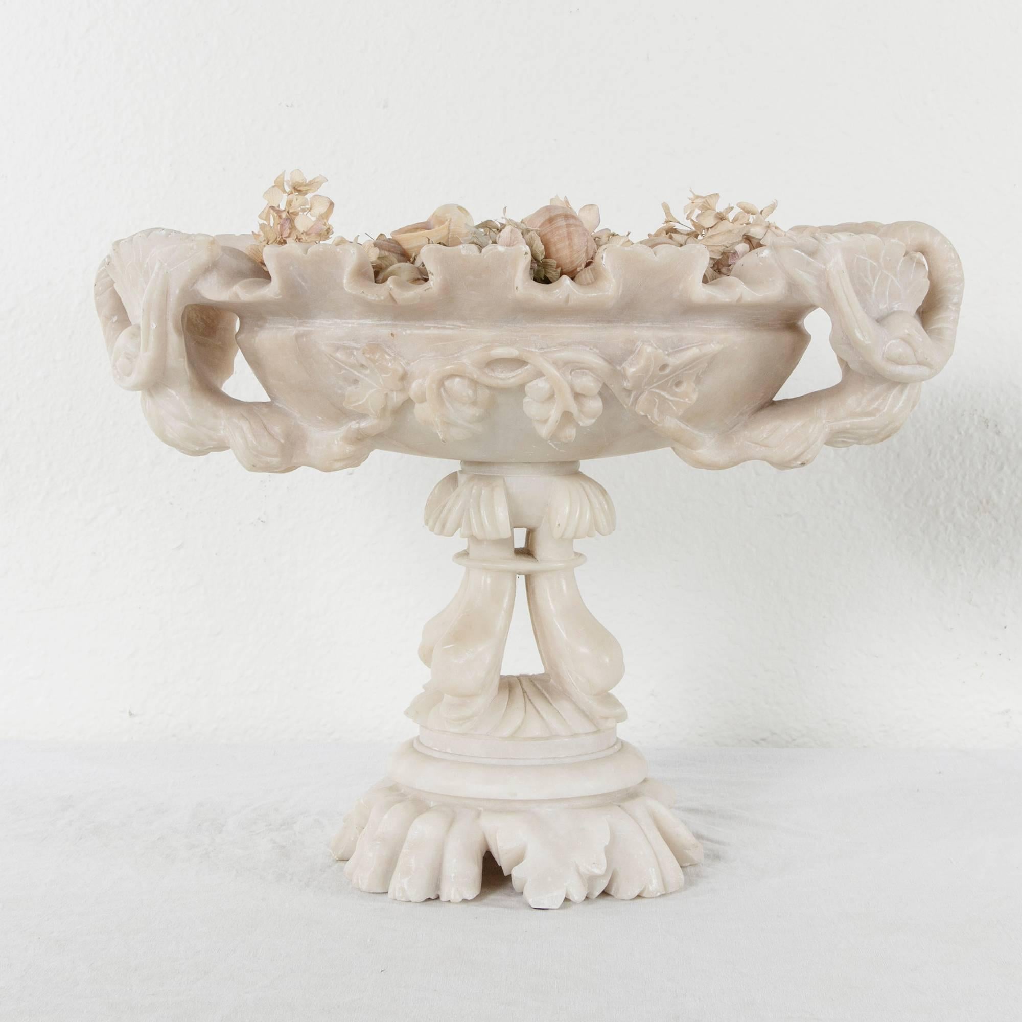Resting on an alabaster base of hand-carved dolphins, the bowl of this compote is adorned with swan handles. The dolphin or Dauphin, in French, represents the heir apparent to the throne of France. The French kings held the beauty of objects in high