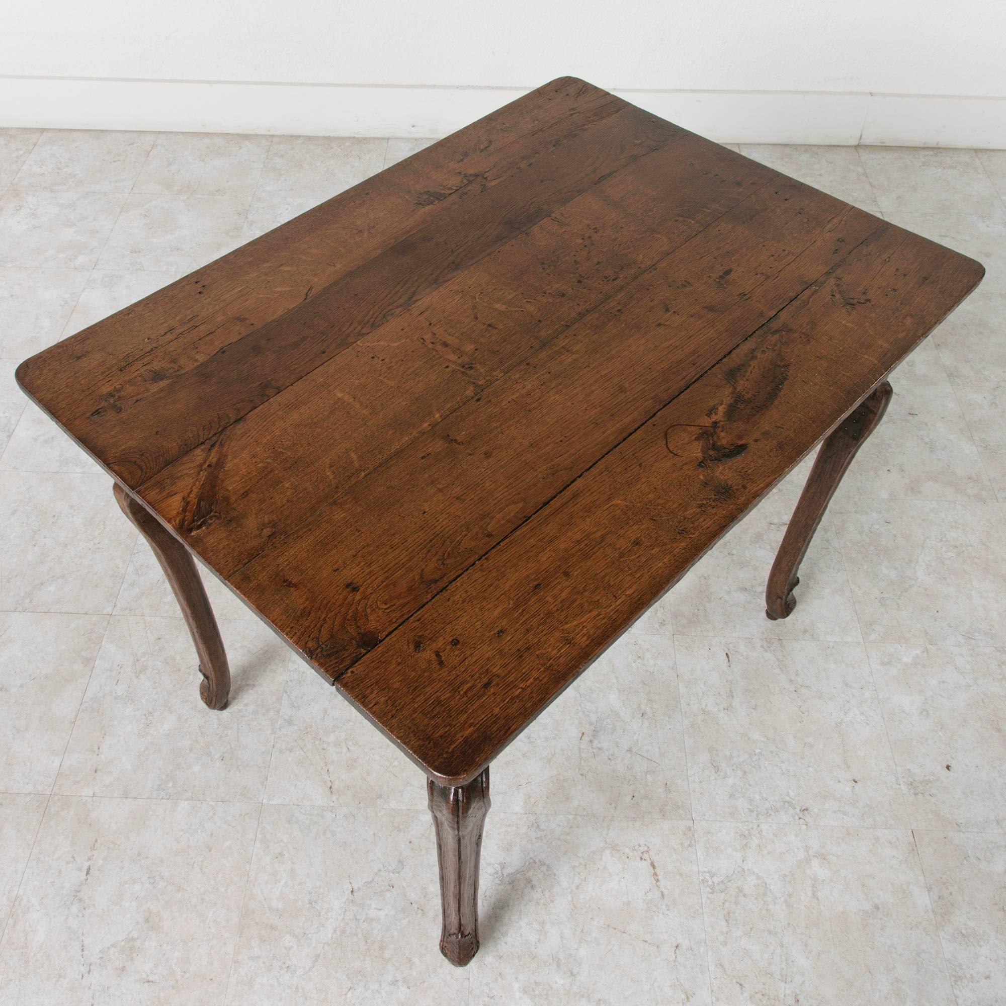 Made of oak, this period Louis XV side table has stood the test of time with its Classic design. Charming and understated, this table features a slight curvature to the leg and rosettes carved into the apron. This rustic, elegant table displays a