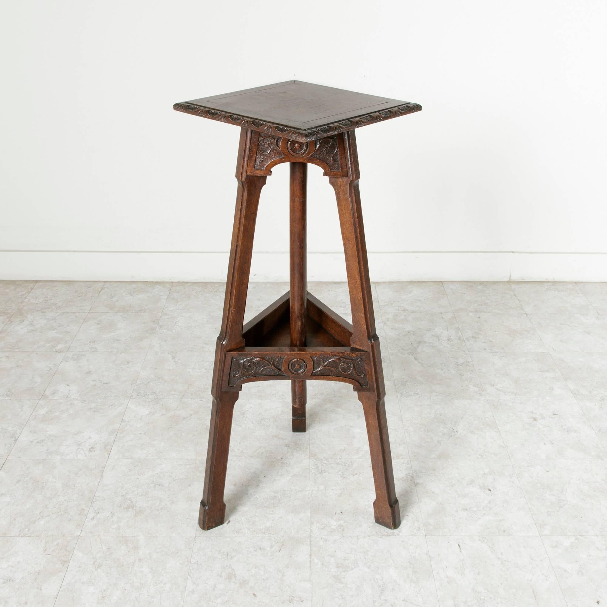 This late 19th century, French sculptor's table is constructed of solid oak. Three high legs joined by hand-carved friezes support its square top with hand-carved border., Its top rotates, allowing the sculpture it displays to be turned to any