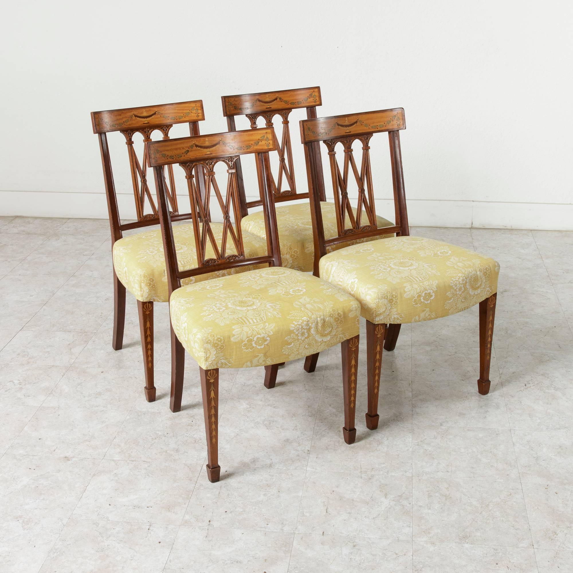A stunning set of four walnut Italian dining chairs from the 19th century. Intricate inlay of a Classic urn and festooning garland in lemonwood and sycamore grace the curved crown of the hand-carved lattice seatbacks. The marquetry garland motif is
