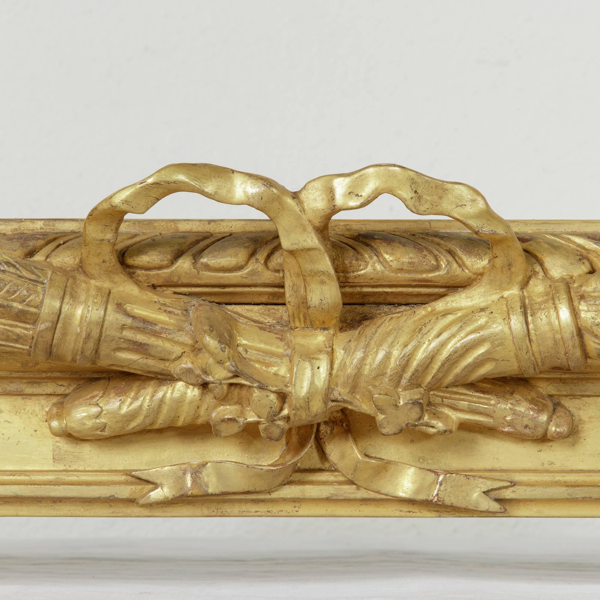 This stunning pair of 19th century window cornices of hand-carved giltwood was originally used as drapery valances in a French chateau. Featuring a Classic Louis XVI motif of crossed torch and quiver with knotted bow and ribbon, this rare pair will