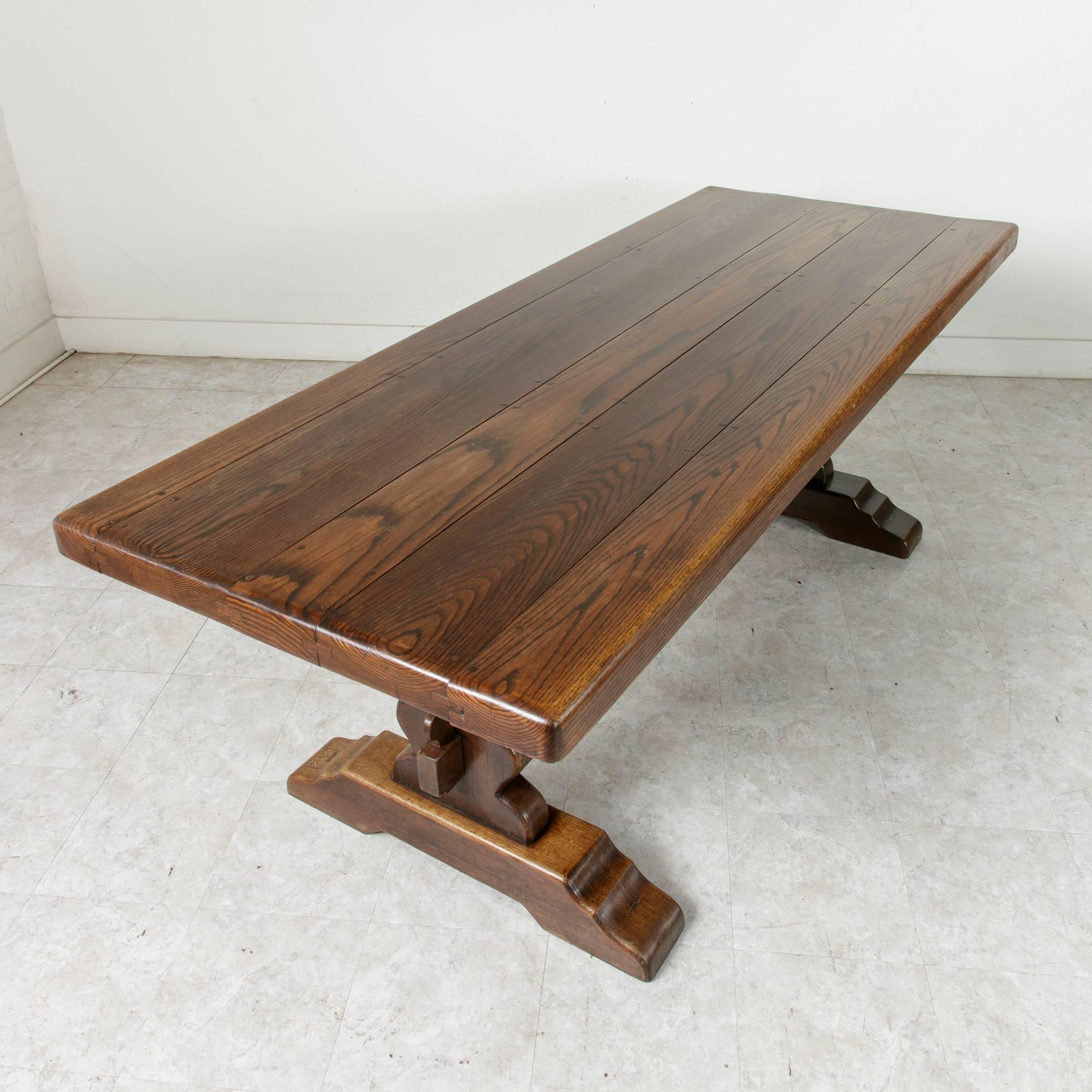 This Normandy monastery table was created by artisans in the first half of the 20th century for use as the principal dining table on a farm. Made of solid oak, the sturdy handmade trestle construction of this piece will last for centuries. The 2 1/2