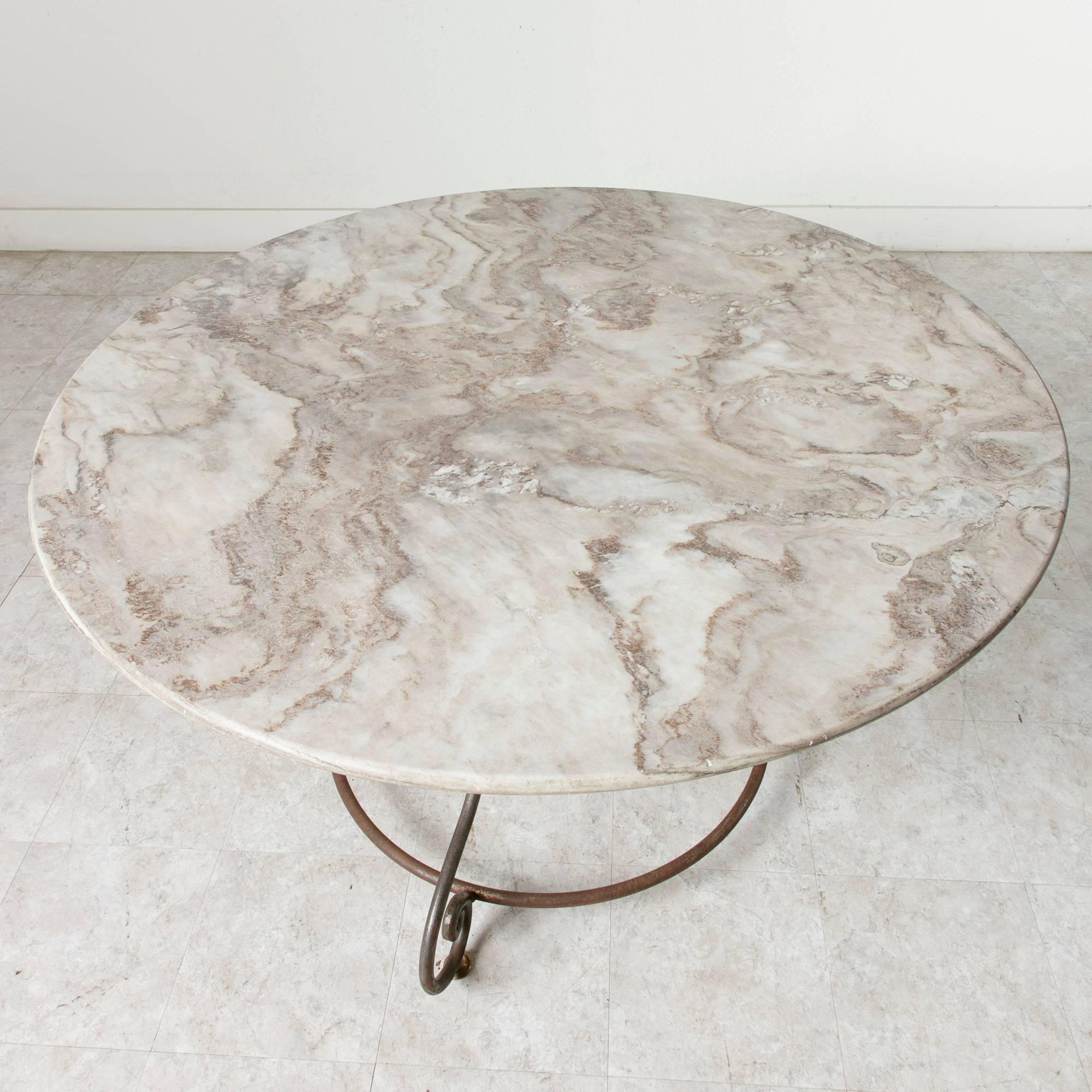 This large French round garden table features an exceptional marble-top resting on an elegant, iron base. A mid-twentieth century table of classical form with a 51-inch diameter, it easily seats six. Ideal for plein air dining in the garden or as a
