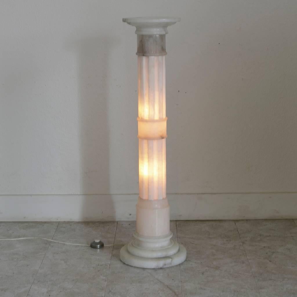 Made of alabaster, this early 20th century French neoclassic column casts a warm glow when lit. Electrified to American standards with two lights inside, it may be turned on or off by means of a foot pedal. At 42 inches high, this elegant pedestal