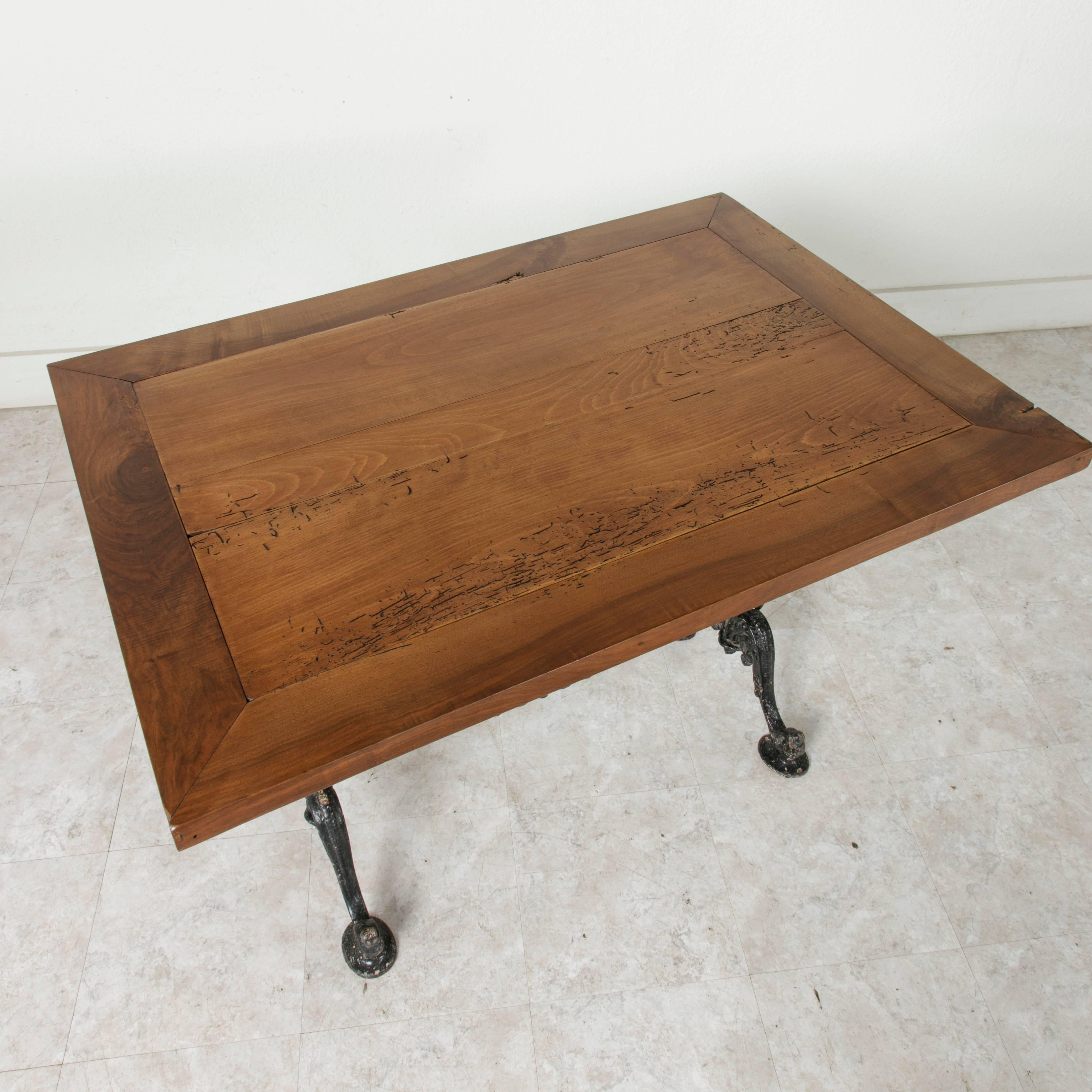 An ideal piece for a breakfast nook or small kitchen, this charming French bistro table displays the mastery of late 19th century cast iron work. A beautifully aged walnut top full of character is supported by an intricate cast iron base with four
