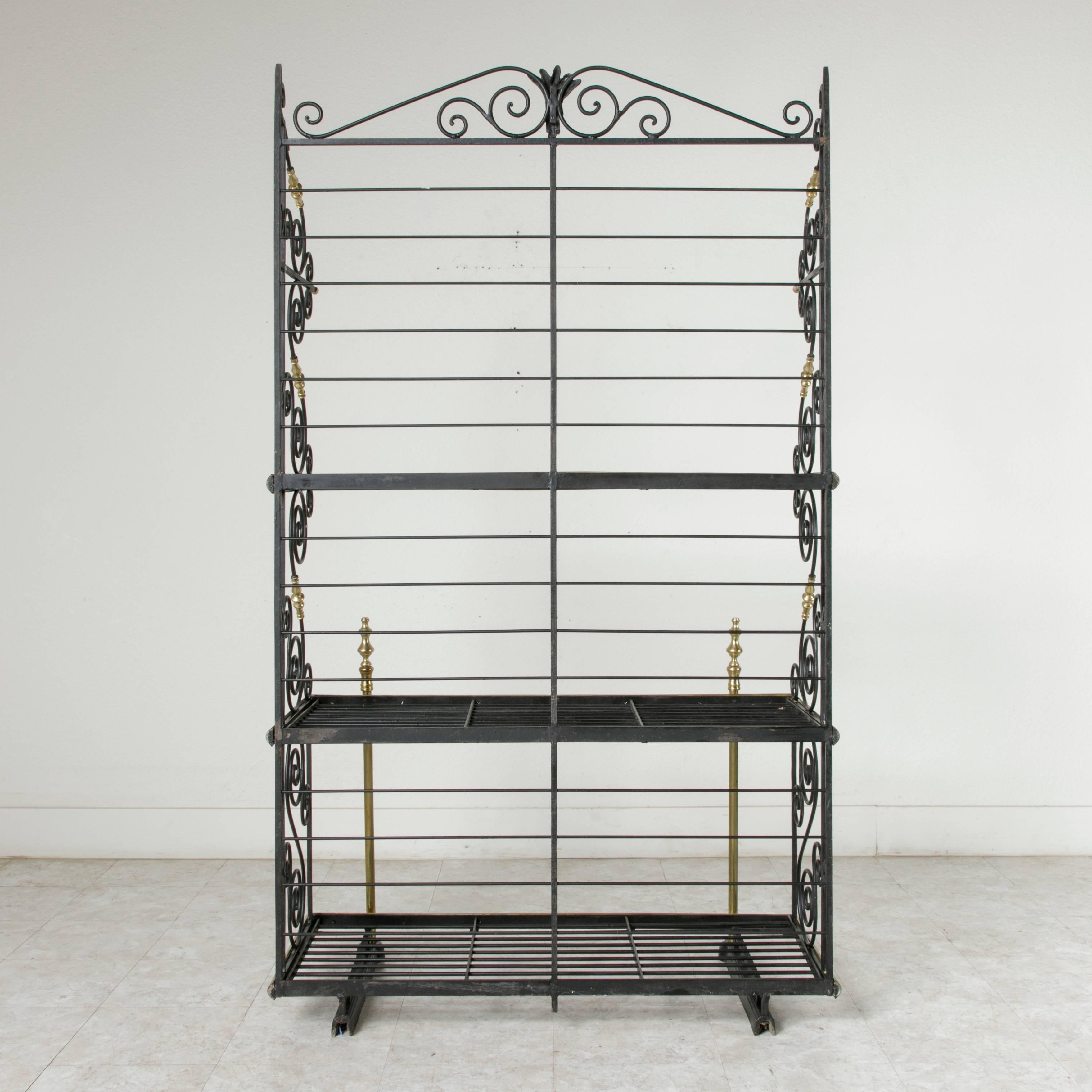 Found in Normandy, this early 20th century baker's rack was originally used in a French bakery. The upper shelf held the long baguettes placed on end or in baskets. Its wrought ironwork features sides of graceful scrolling with hand-hammered tips,