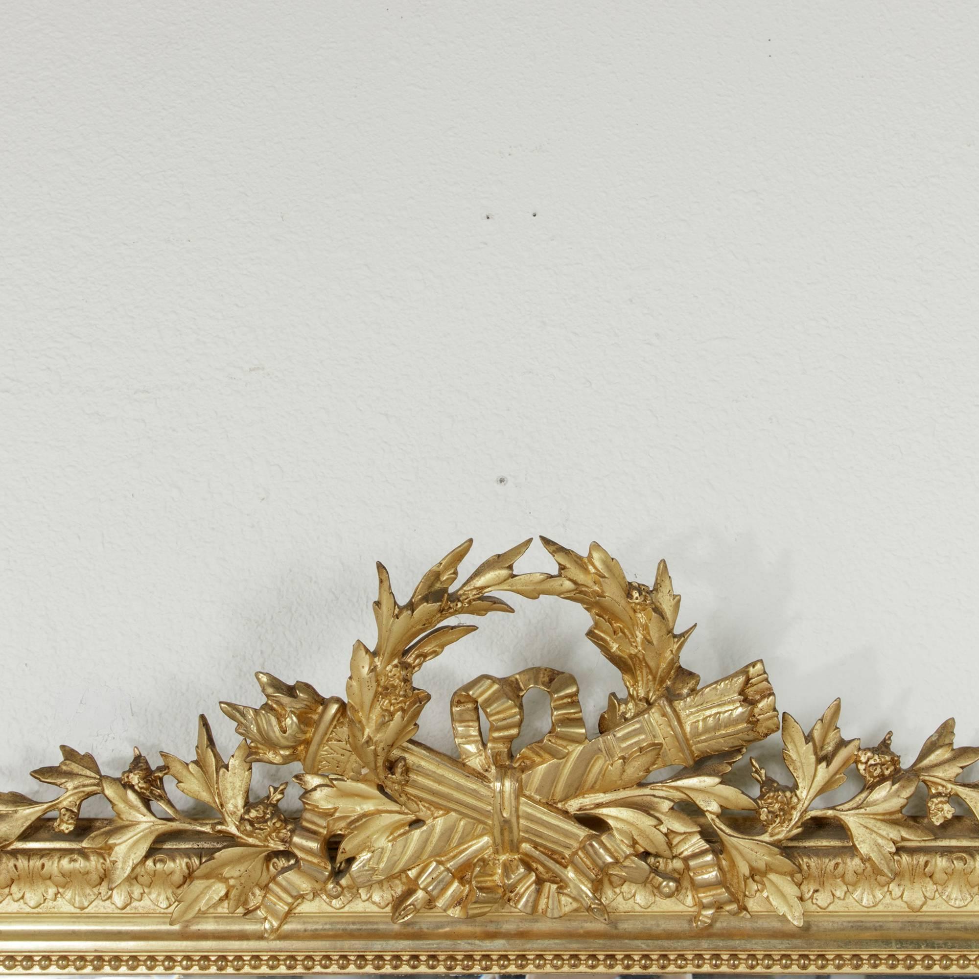 Ideal above a mantel, buffet or chest of drawers, this elegant late 19th century giltwood Louis XVI style mirror boasts its original beveled glass. Its ornate frame is hand-carved with Classic Louis XVI acanthus leaves and a border of fine beading.