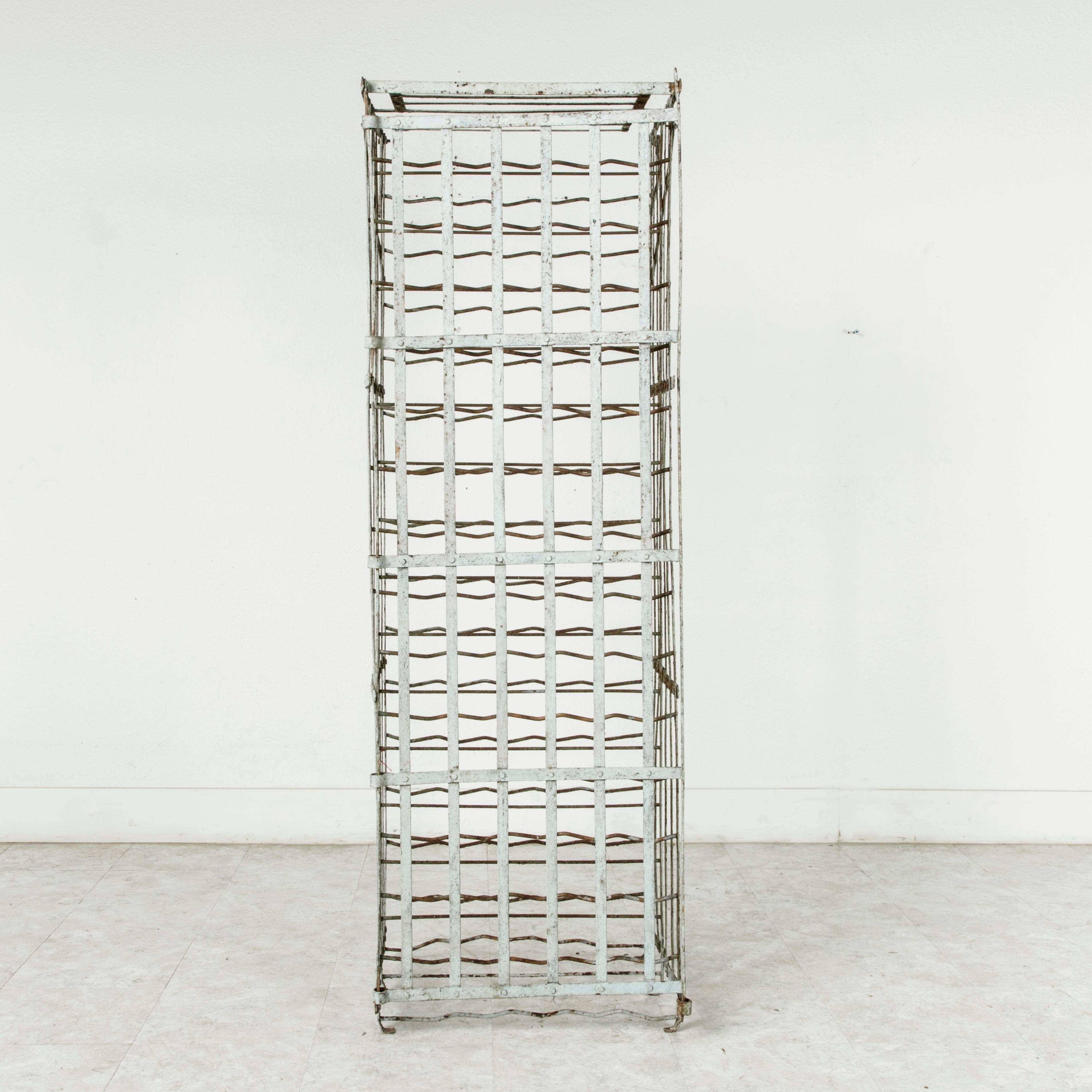 Manufactured during the 1920s, this riveted iron wine cage or wine rack was originally attached to the wall in a French wine cellar though it may also remain freestanding. Painted in a pale blue green, this piece has a capacity of 140 bottles, may
