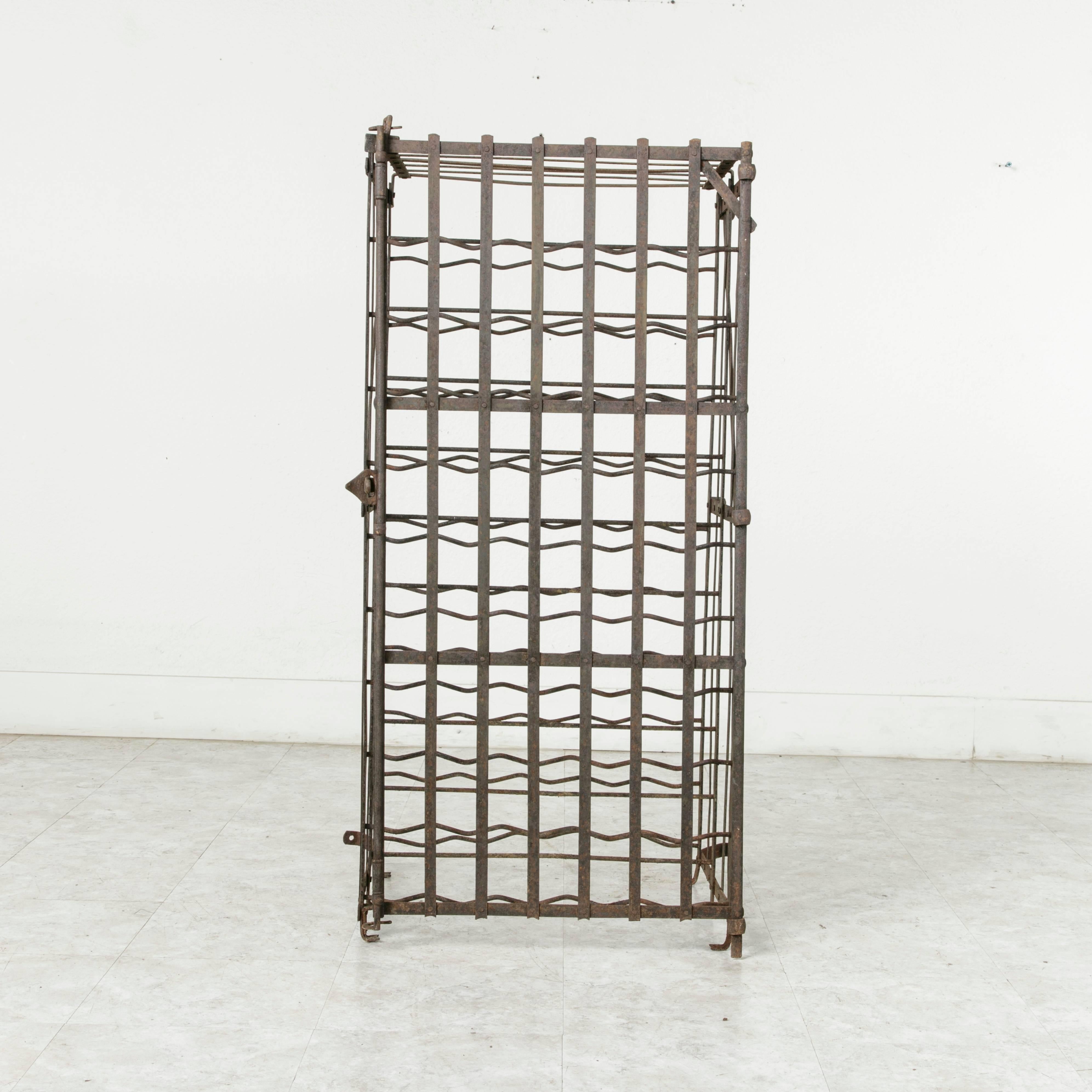 Originally used in a French wine cellar, this riveted iron wine cage from the early 20th century holds up to 100 bottles. This wine rack may either be bolted to the wall or remain freestanding, and it may be locked with a padlock. Smaller in size