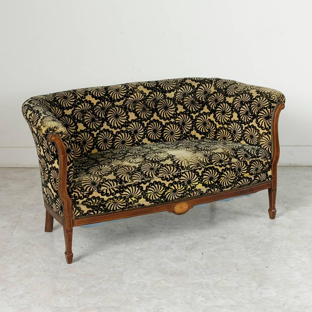 A rare find in French Art Deco period pieces! This chic small-scale settee or sofa has the Classic lines of the furniture of the period but is set apart by its unusual details. Its mahogany frame is finely inlaid with lemonwood and sycamore rosettes