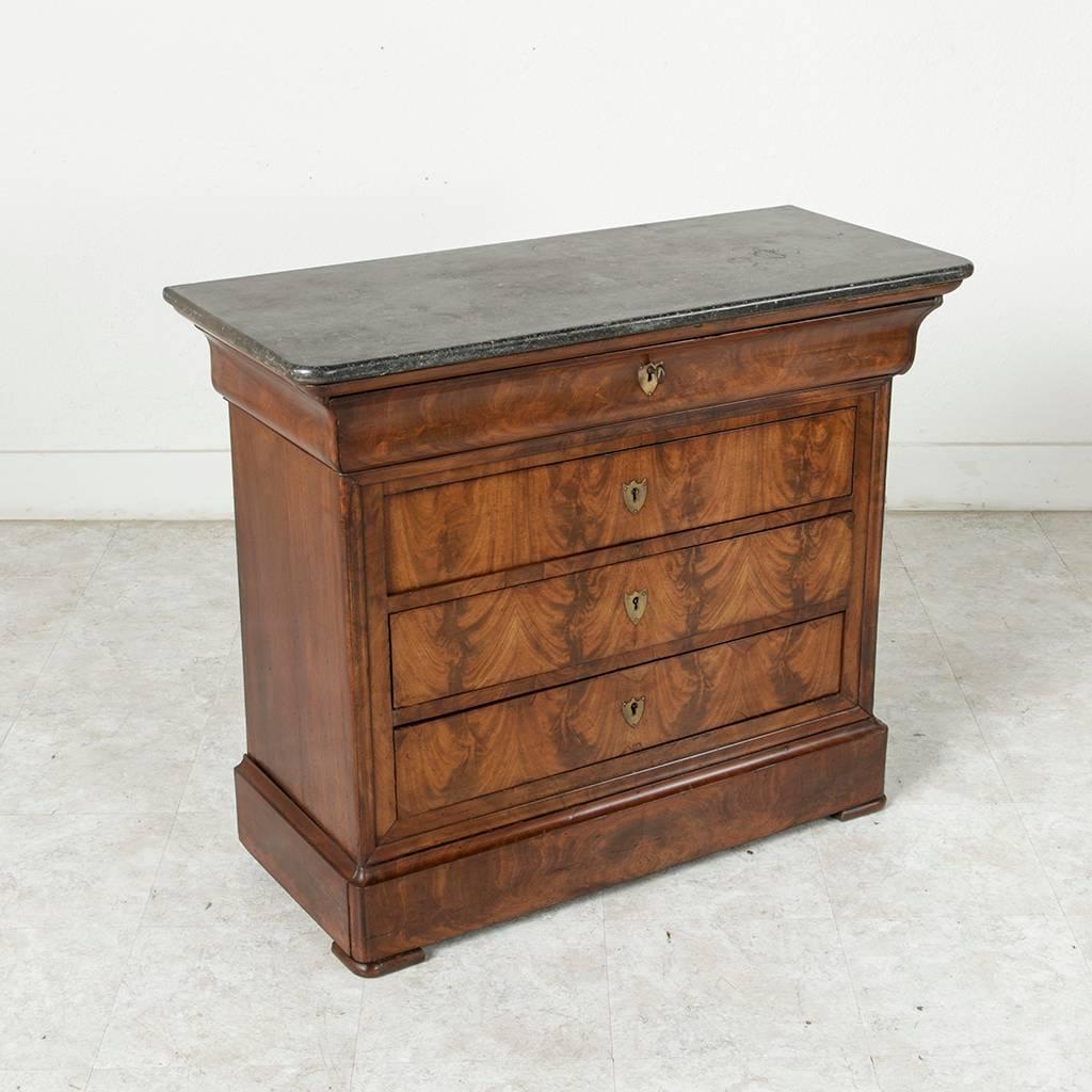 Rare for its small size, this bookmatched flamed mahogany Louis Philippe period commode or chest features four drawers of dovetail construction and a black marble top. Its unusual dimensions of 38 inches in width and only 16.5 inches in depth make