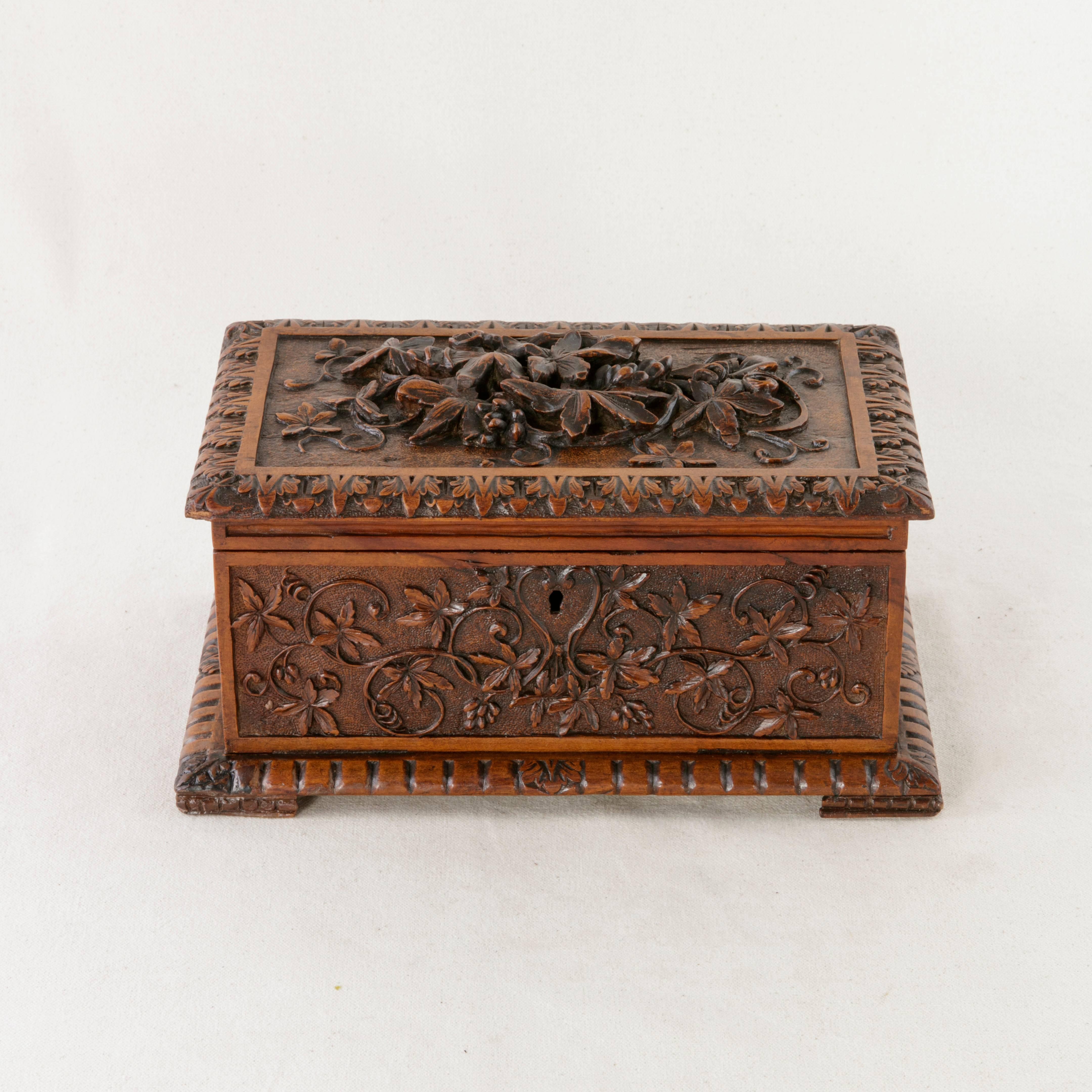 A Classic example of Black Forest artistry, this box features lavish hand carvings on all four sides as well as the top. A border of leaves with fleurs-de-lys corners surrounds the ornate lid. Its center carvings of deep relief include vines,