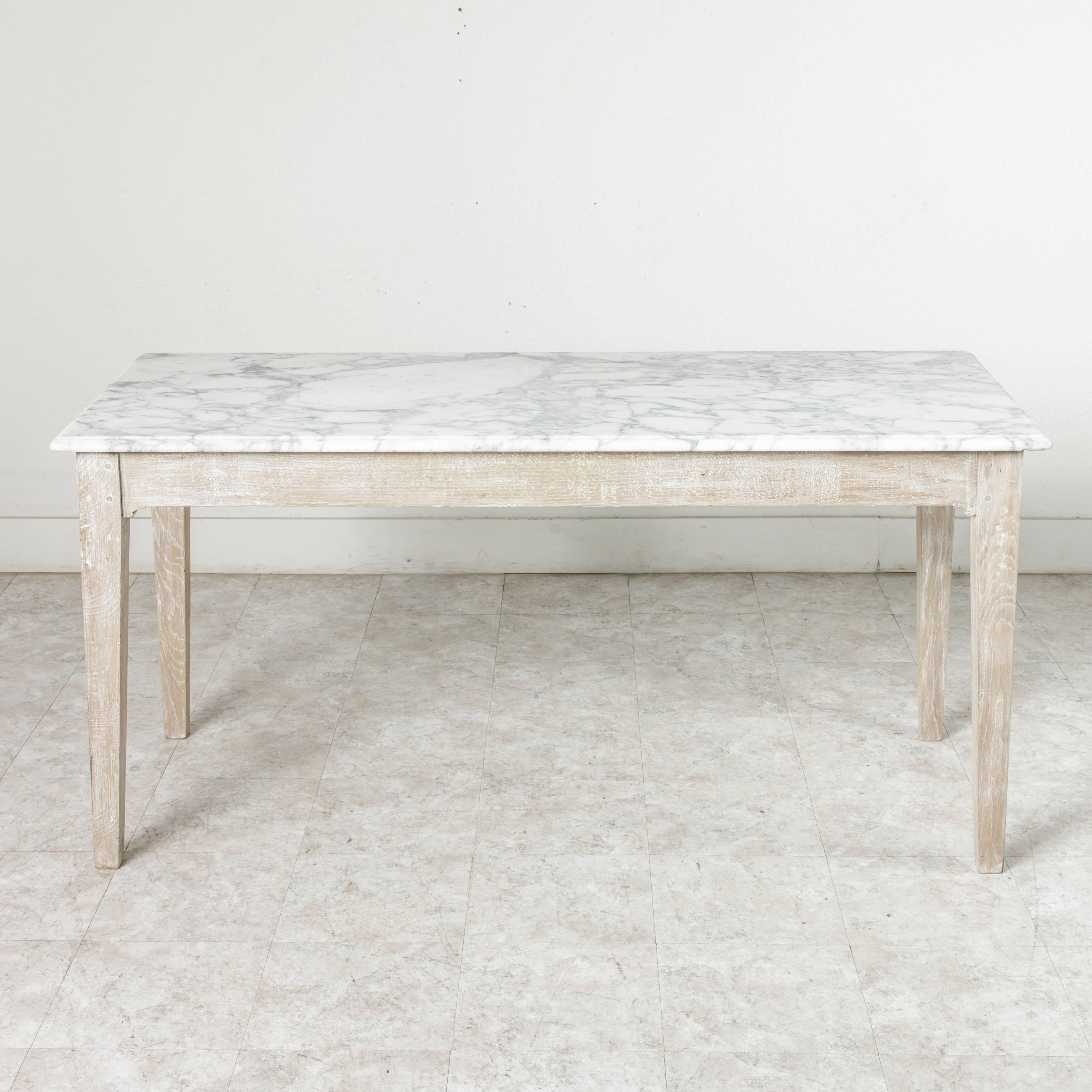 This 19th century French oak pastry table features a beautiful solid Carrara marble top, the surface of which was originally used to roll out dough. The hand pegged oak base with tapered square legs has been cerused, giving it a friendly washed