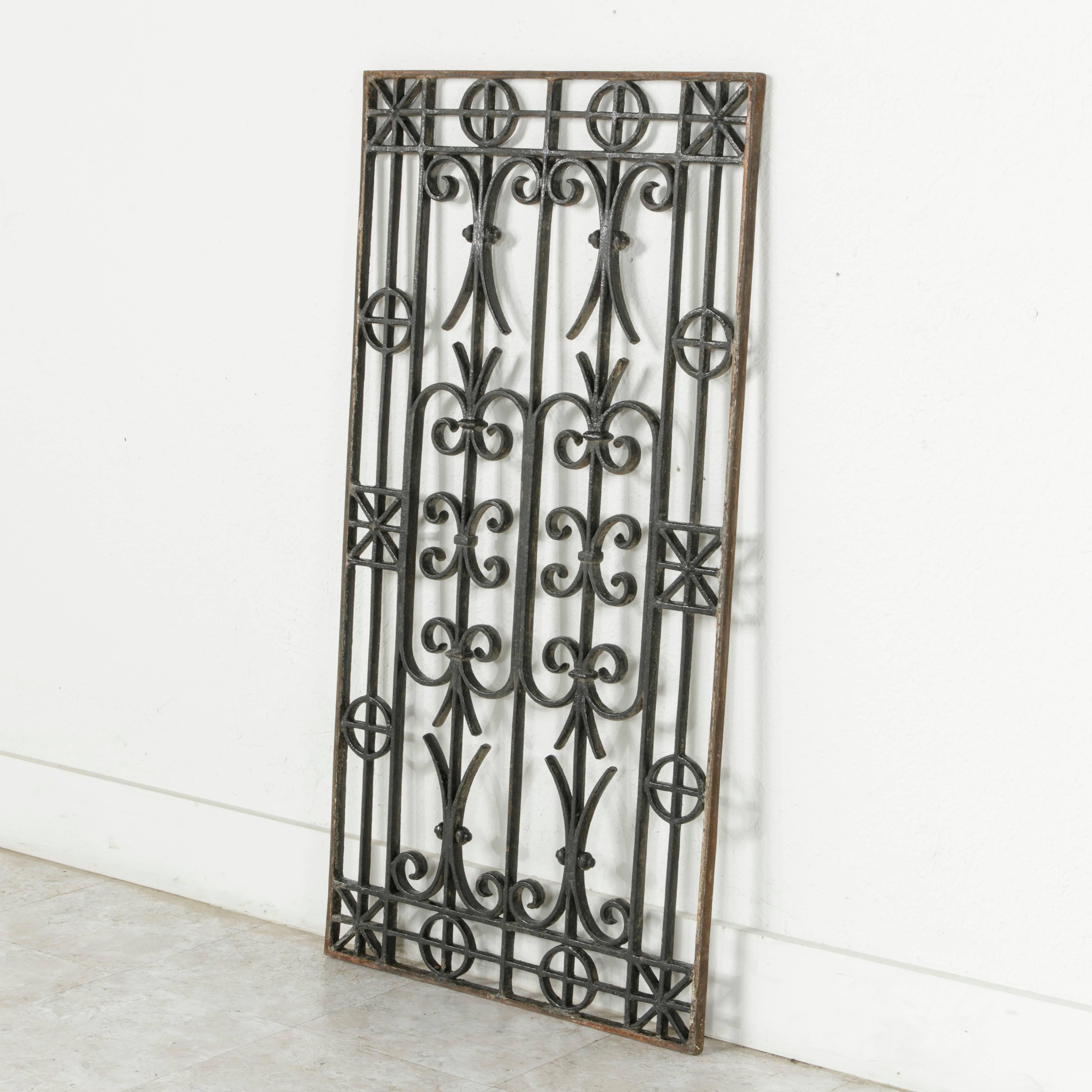 This late 19th century cast iron grill or grate features a design of intricate scrolling with a border of geometric shapes. With its symmetrical design, it can be hung on a wall in either the horizontal or the vertical. It is also ideal for