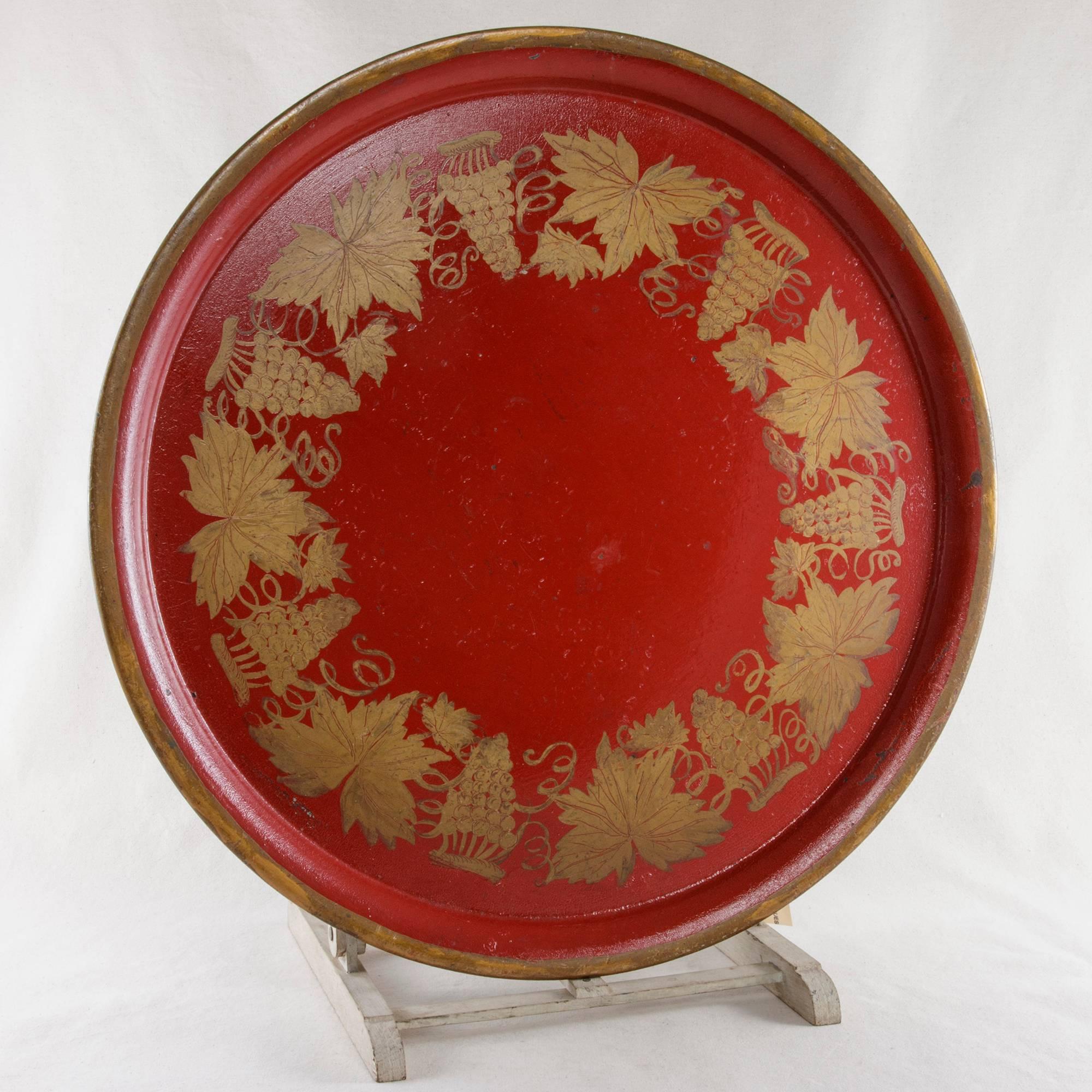 This Napoleon III period tole tray features a red background with hand-painted gold grapes, grape leaves and vines around the inside perimeter and a gold border around the outer edge. The black back is signed A. Dereaune, Paris. An ideal decorative