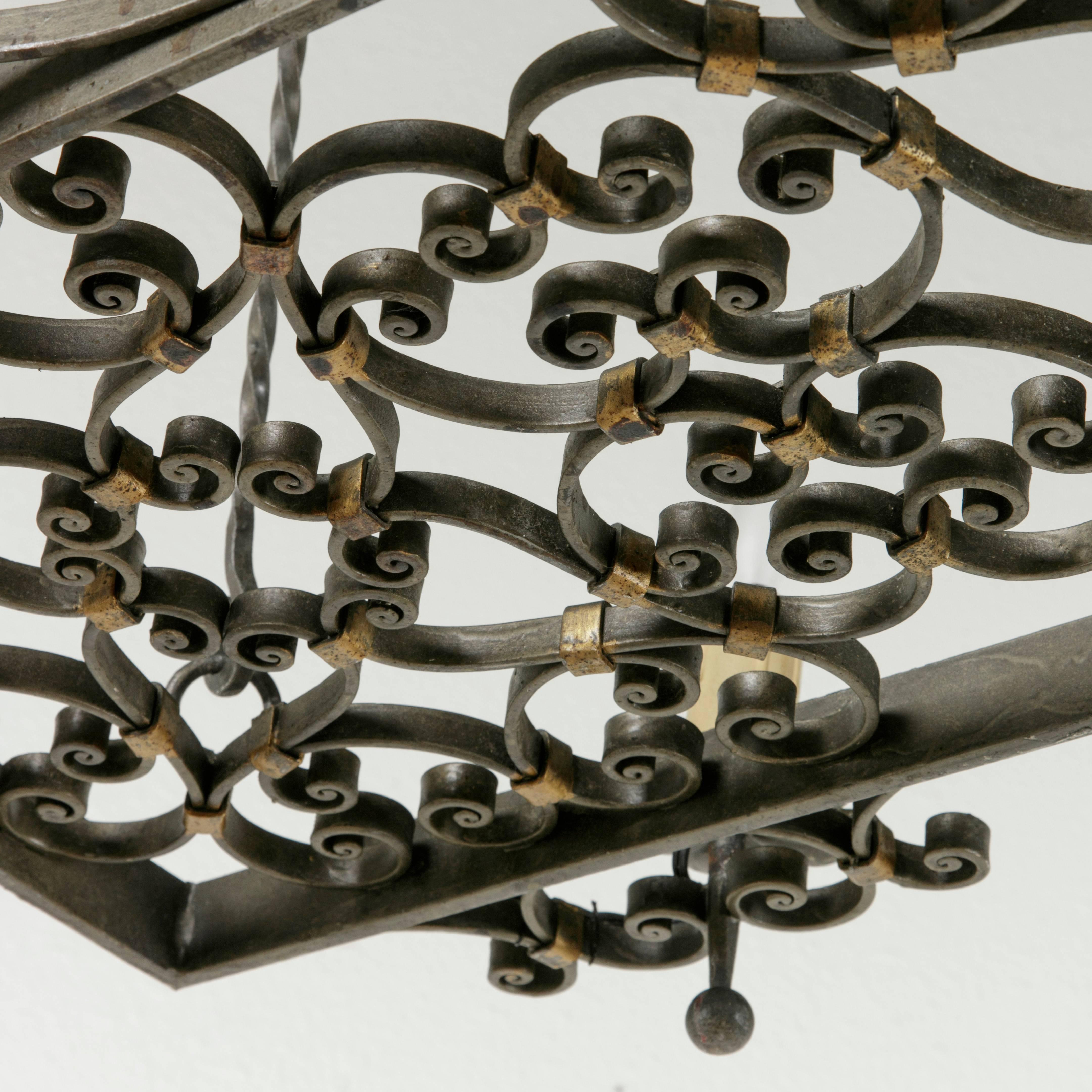 Originally from the region of Normandy, France, this iron chandelier features elegant hand-forged iron scrolling detailed with painted gold iron bands. Electrified to American standards, this chandelier has six lights that line the outer edge of its
