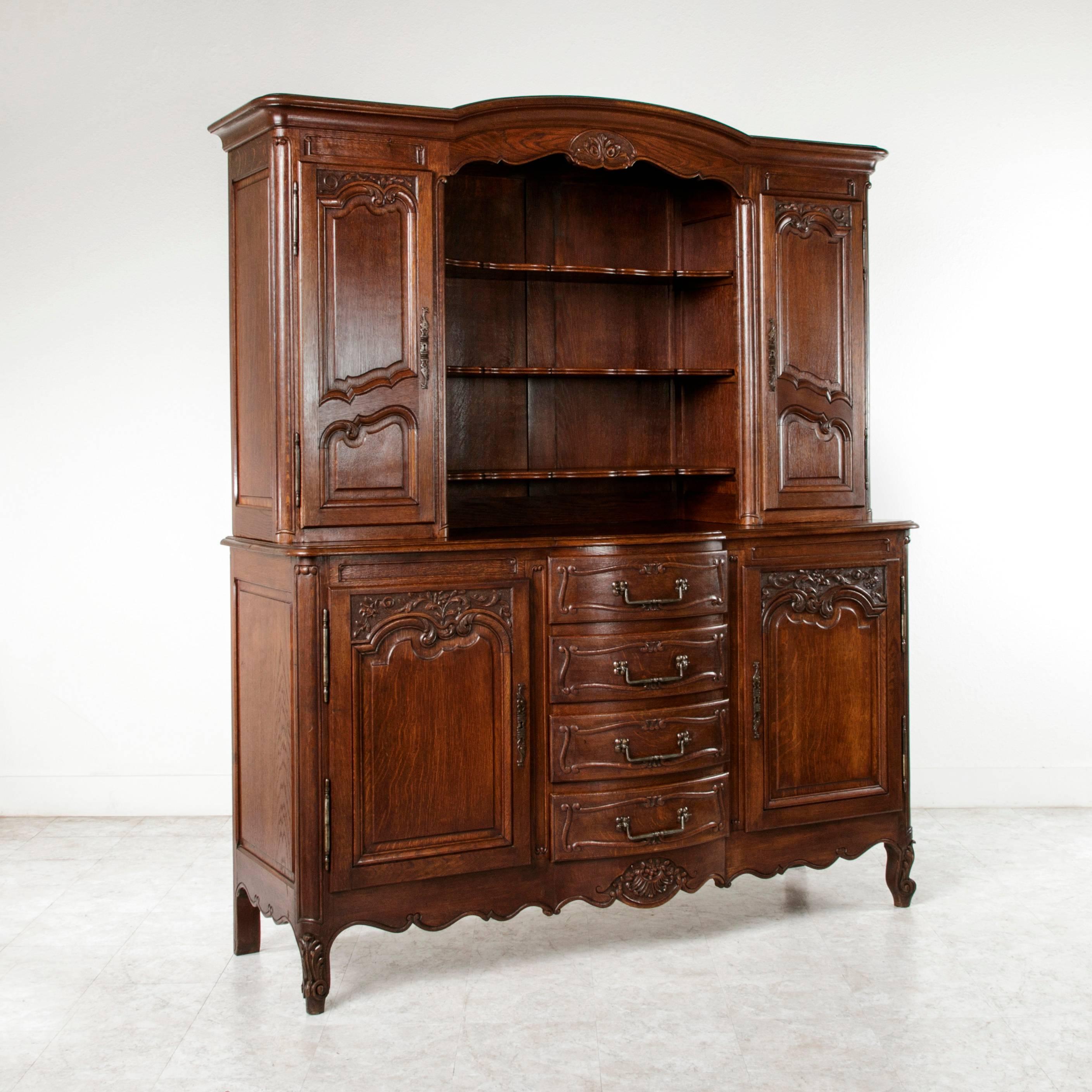 The French vaisselier was the quintessential dining room piece in a French country home. Found in Normandy, France, this early twentieth century Louis XV style oak vaisselier or buffet deux corps features solid panelled sides, a bonnet top, and four