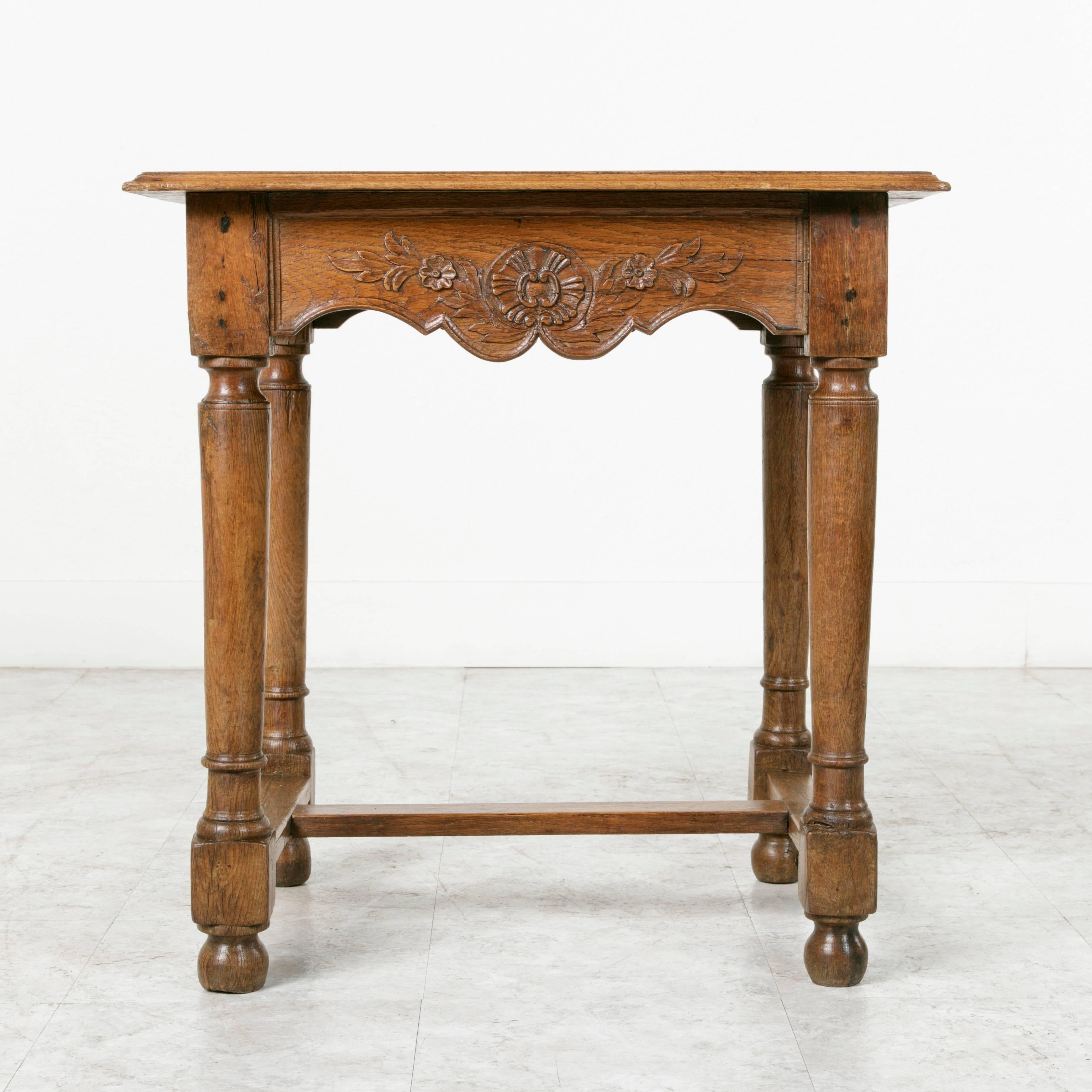 Originally from the Haute-Saone region of France, near the Swiss and German borders, this late 19th century oak side table features hand pegged die joints and hand carvings on all four sides. Each side's carvings include a central cartouche flanked
