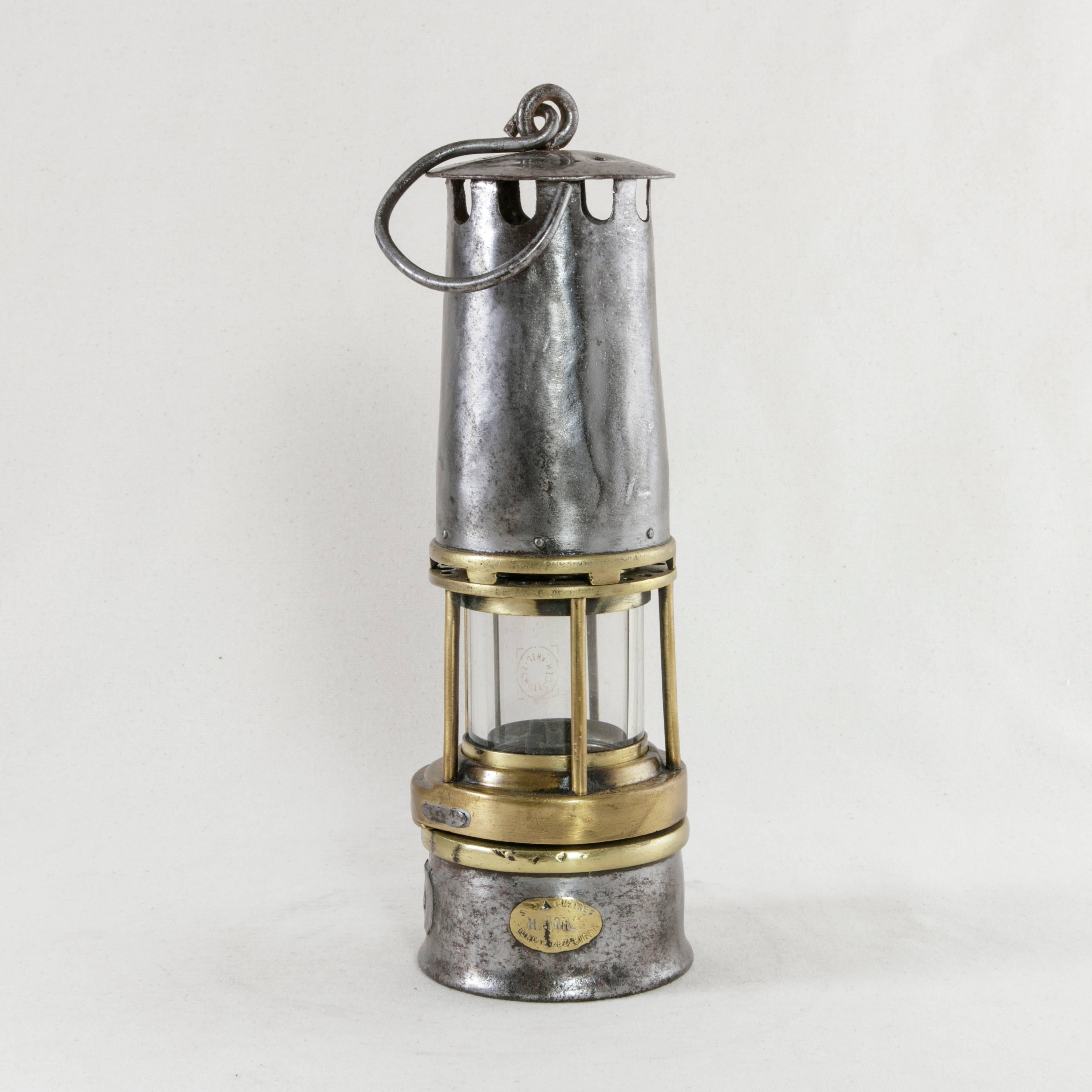 This Belgian steel miner's lantern, circa 1900 features brass trim around its original glass casing. A brass plaque labeled H. Joris, S.N.A. Usines, Liege, indicates its fabrication by the Joris Company at their factory in Liege, Belgium. Additional