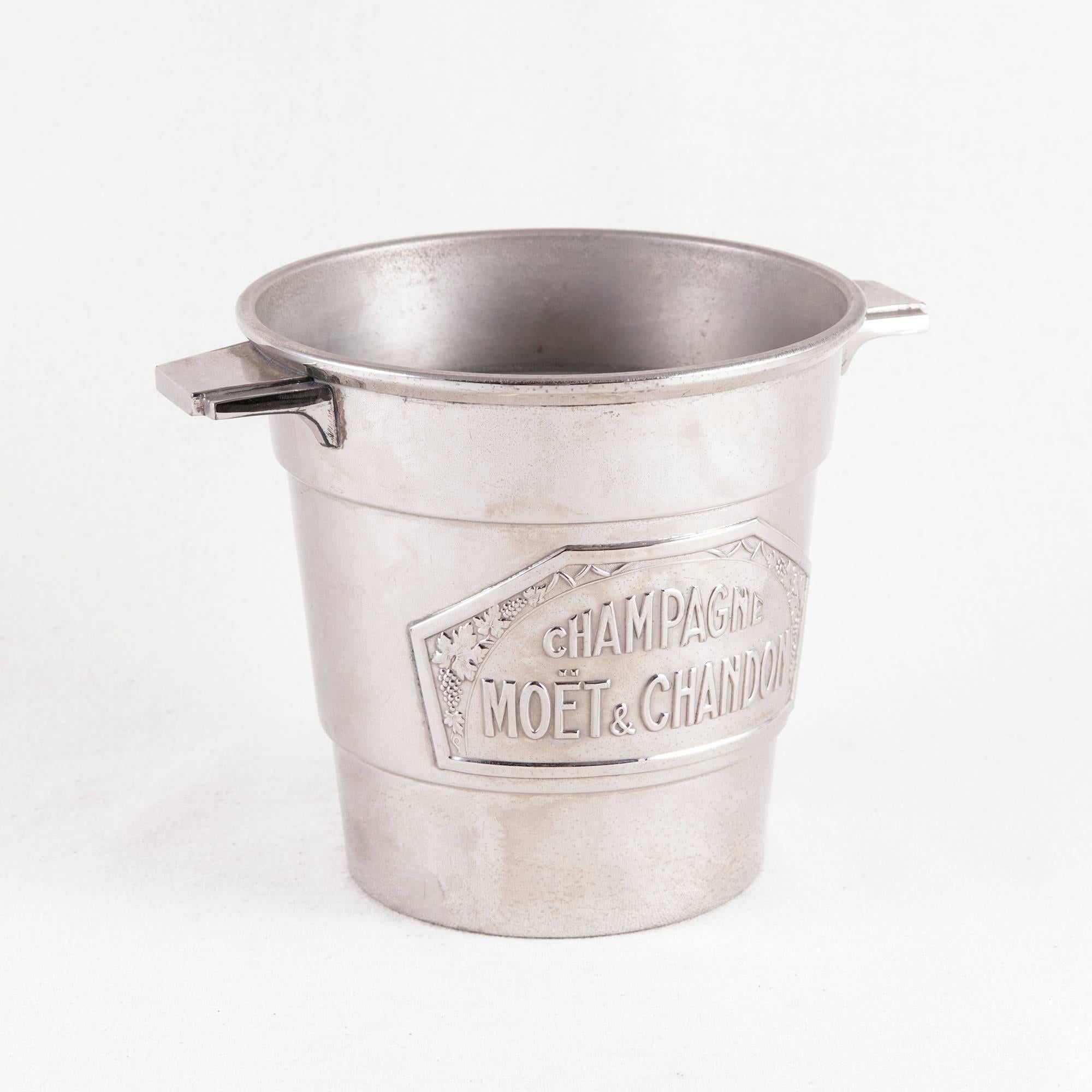 This small-scale Art Deco period silver plate champagne bucket features a label of the name of the renowned champagne producer, Moet et Chandon, flanked by grapes and grape leaves. With its unusual size intended for half bottles of champagne, this