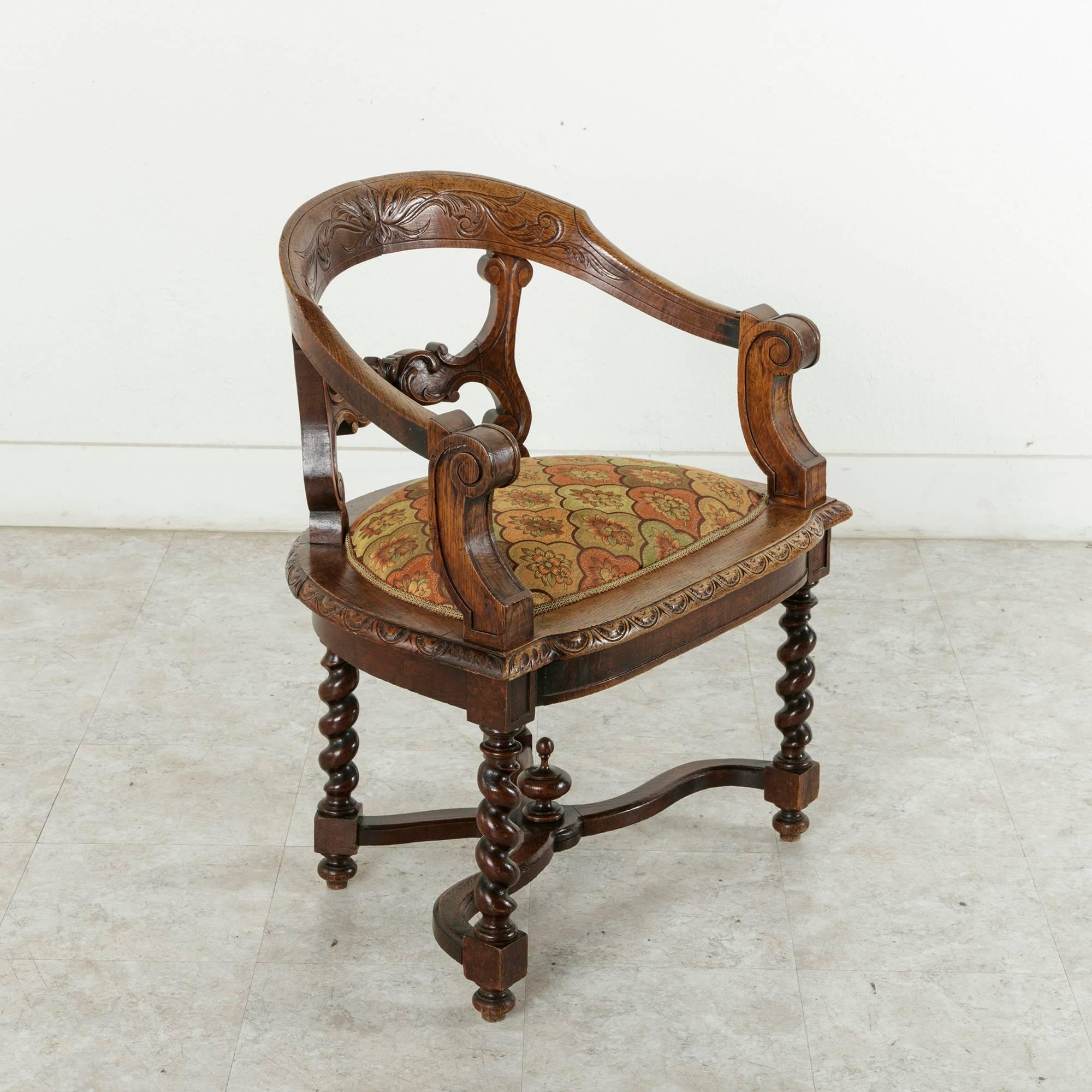 This hand-carved French oak armchair in the Renaissance style of Henri II features barley twist legs joined by an X-stretcher capped with a central finial. Its ample 27-inch wide seat is detailed with carving all around, and its low arms were