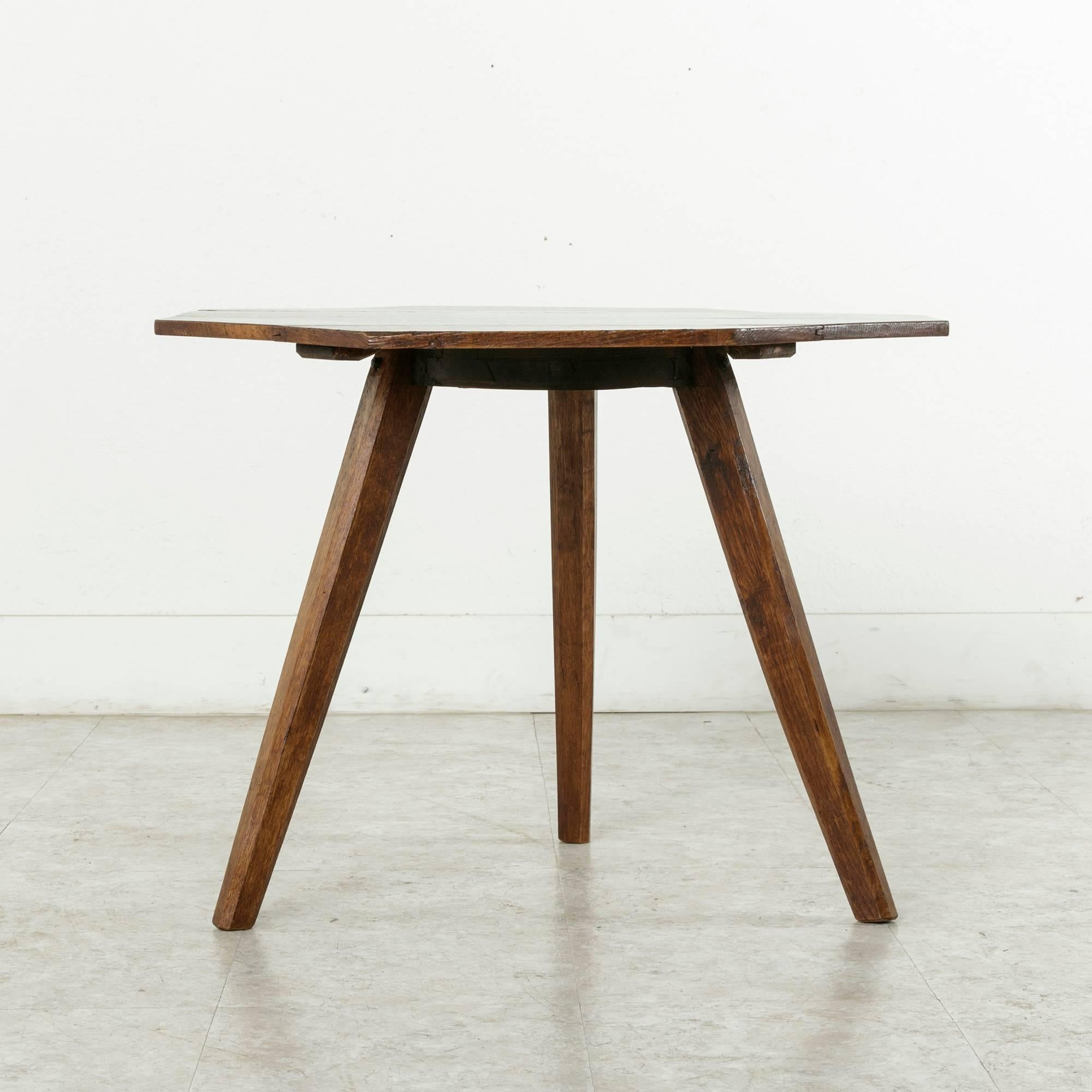 This artisan-made oak side table is constructed of an octagonal top mounted on a hand hewn tripod base with tapered legs. Found in Normandy, France, its 22-inch height makes it ideal between two chairs, next to a sofa, or as a unique coffee table,