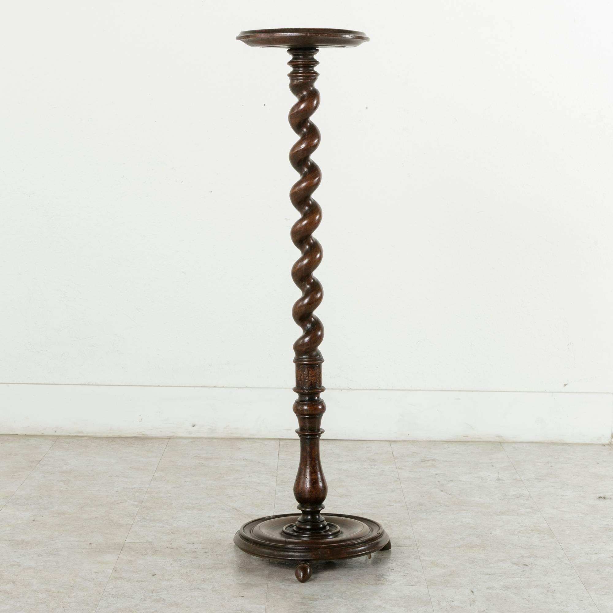 Having stood the test of time, this 17th century Louis XIII period pedestal, hand-carved from French walnut, features a central barley twist column fashioned from a single piece of wood. Its base stands on three ball feet, and its upper platform has