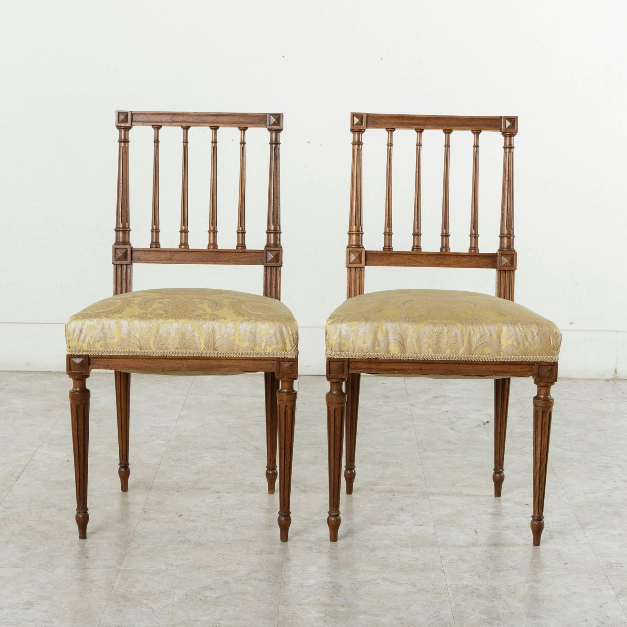 This pair of hand-carved French walnut side chairs in the Louis XVI style dates to the late nineteenth century. Featuring tapered fluted legs with carved diamonds at the die joints, they have been recently re-upholstered in yellow silk. As opera