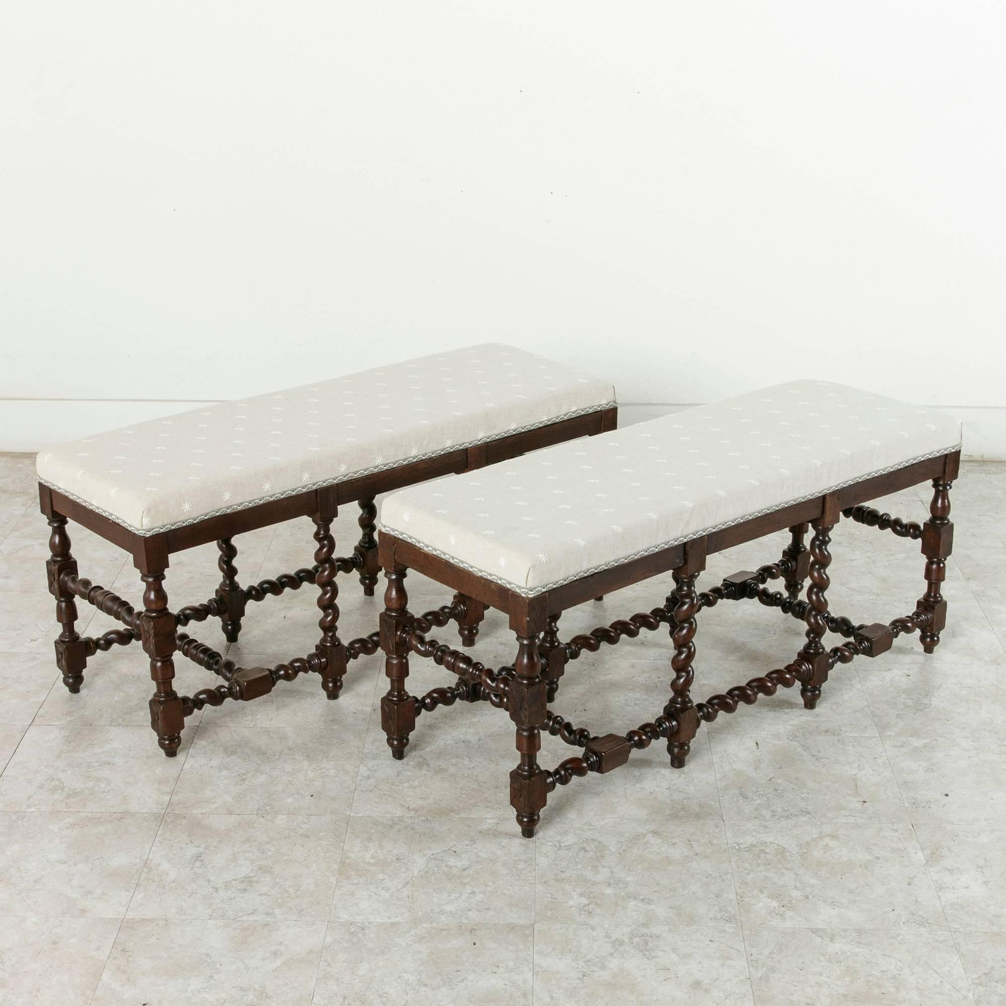 This pair of hand-carved oak banquettes or benches feature barley twist legs and stretchers. Each bench has eight legs joined by multiple barley twist stretchers for exceptional stability. Recently re-upholstered. Priced separately, circa 1900.