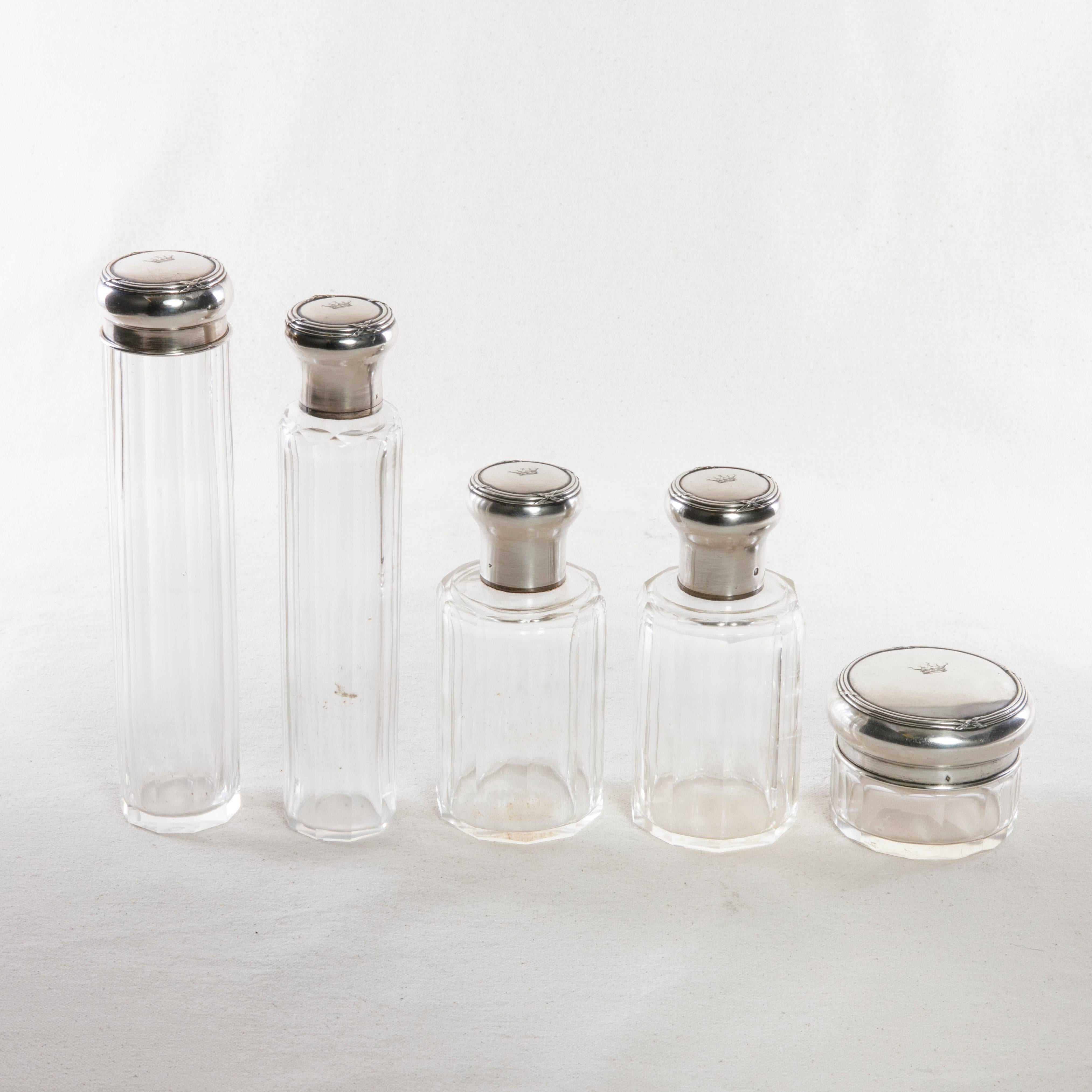 This set of five crystal vanity bottles features sterling silver lids with Louis XVI detailing. The engraved crowns on the lids indicate their previous ownership by a French count. The inside of the lids are marked E. Pinteaux Paris, a known