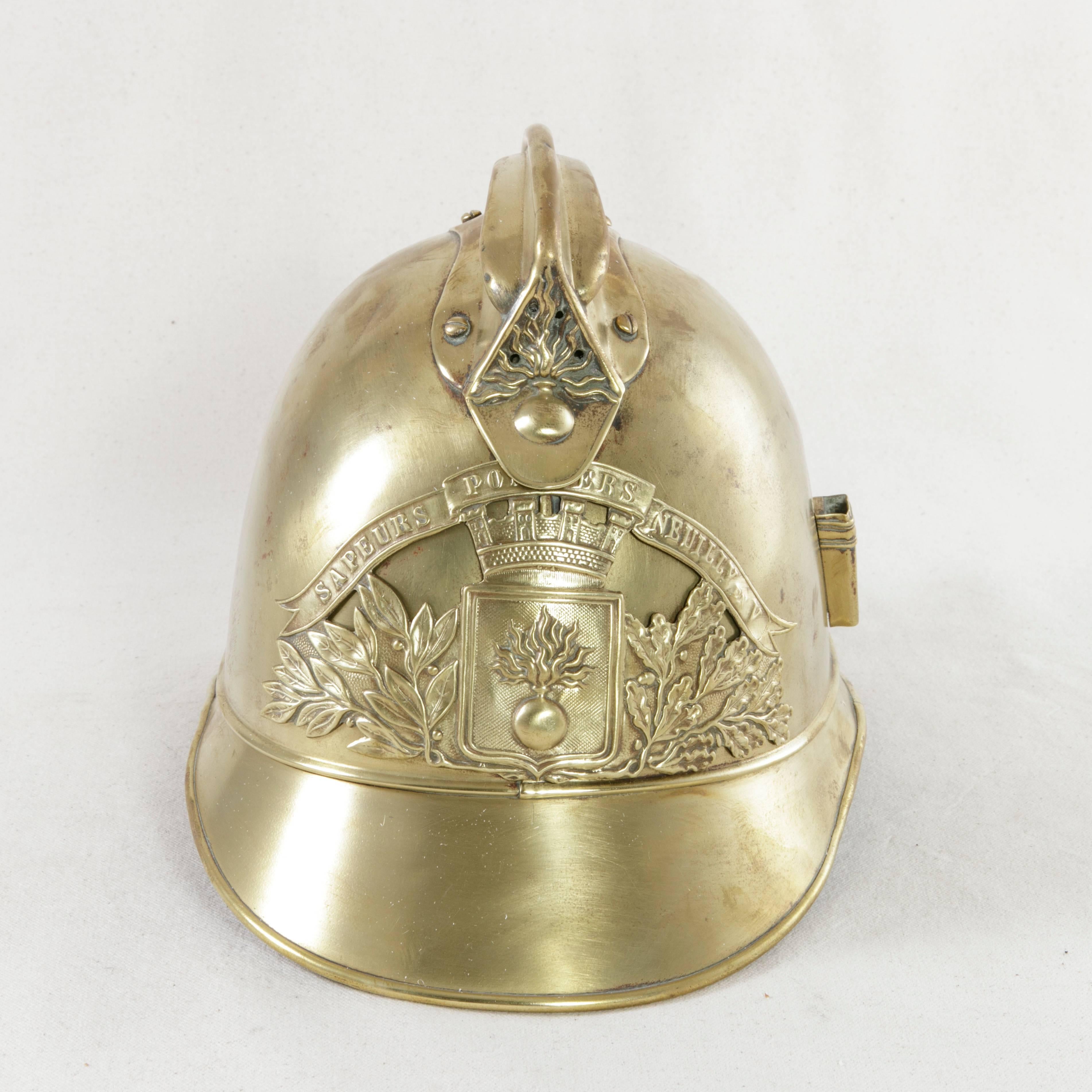 Fitted with its original leather chin strap, this French brass fireman's helmet takes the form of a French military helmet, a style frequently seen during the First World War. The front plate of the helmet bears the classic French fireman symbol of