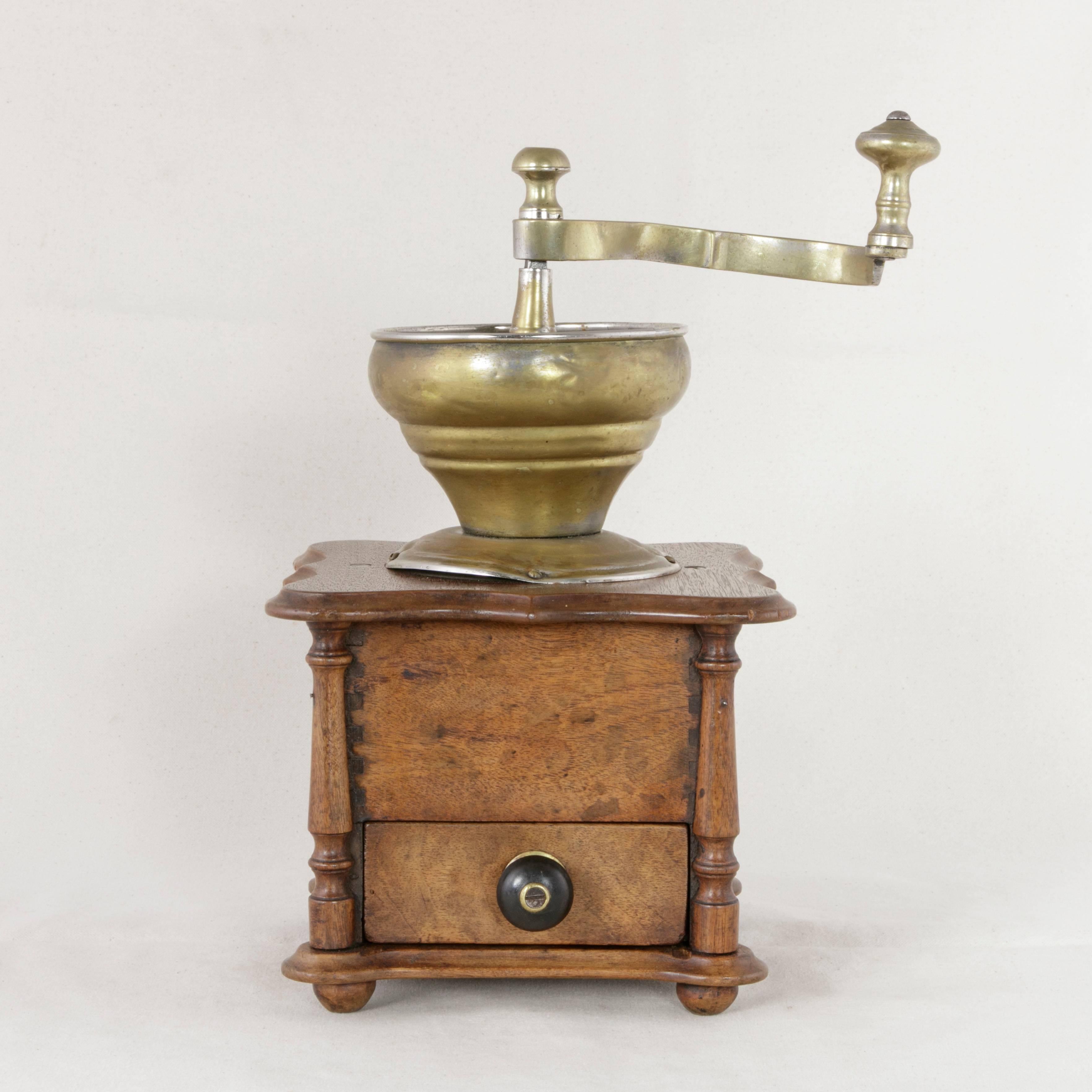 This late 19th century French walnut coffee grinder features a brass funnel at the top where the coffee beans would be introduced and ground by turning its brass crank. A lower drawer with an ebonized wooden knob allowed for retrieval of the