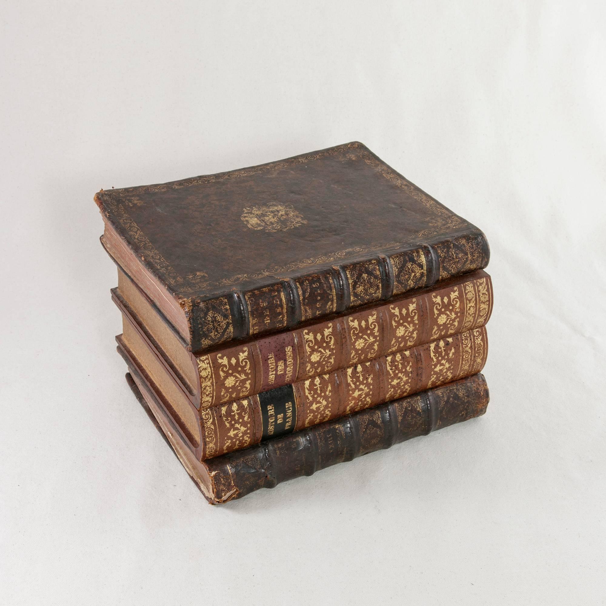 Concealed in a stack of leather bound books with gold tooling, this early 20th century liqueur box features a set of six crystal glasses marked Baccarat on the bottom. The glasses stand three inches high with a diameter of two inches. Individual