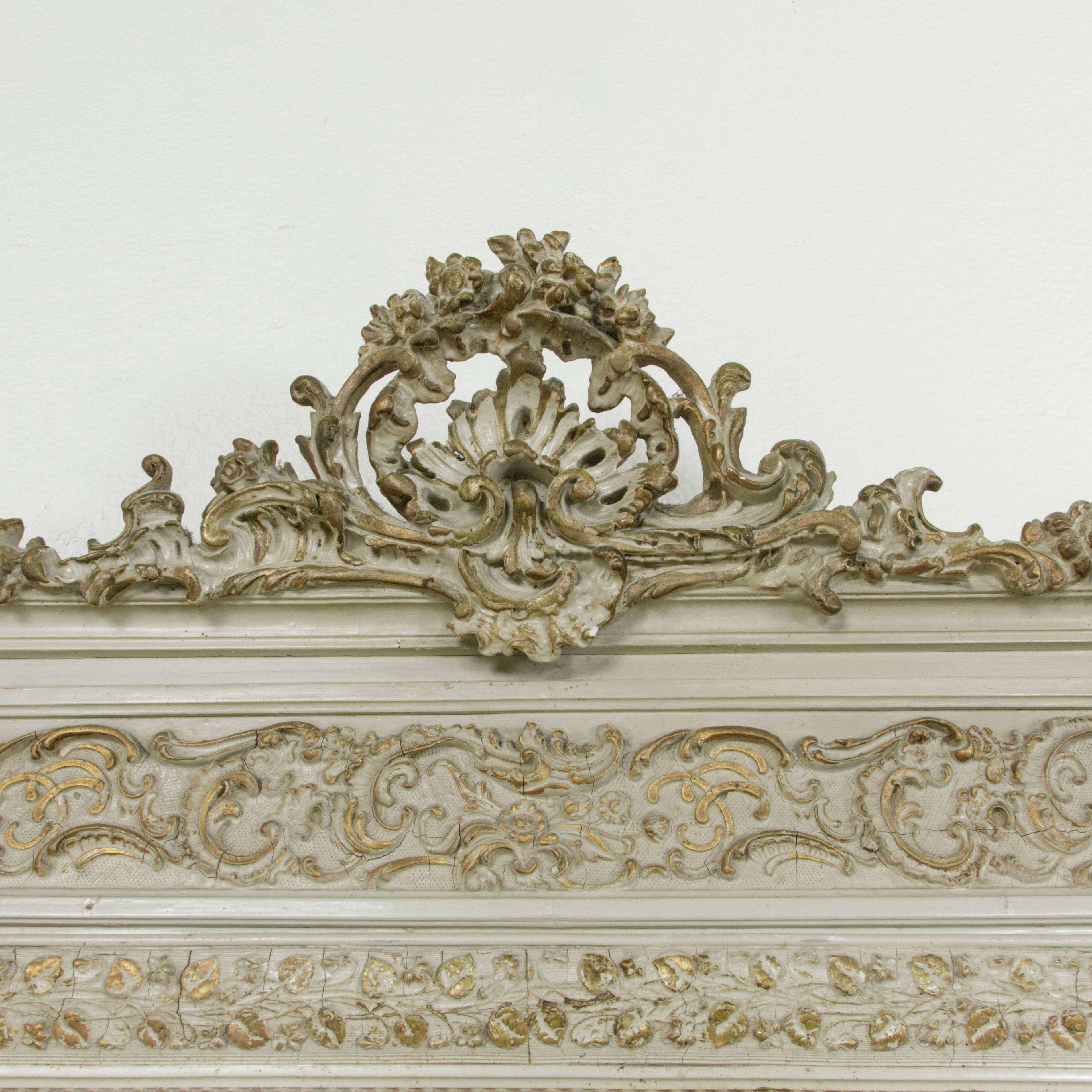 Originally hung above a fireplace mantle, this mid-19th century Napoleon III period painted mirror features hand carving of Louis XV inspired motifs that include a scalloped shell and flourish at the top and scrolling, beading, and florets around